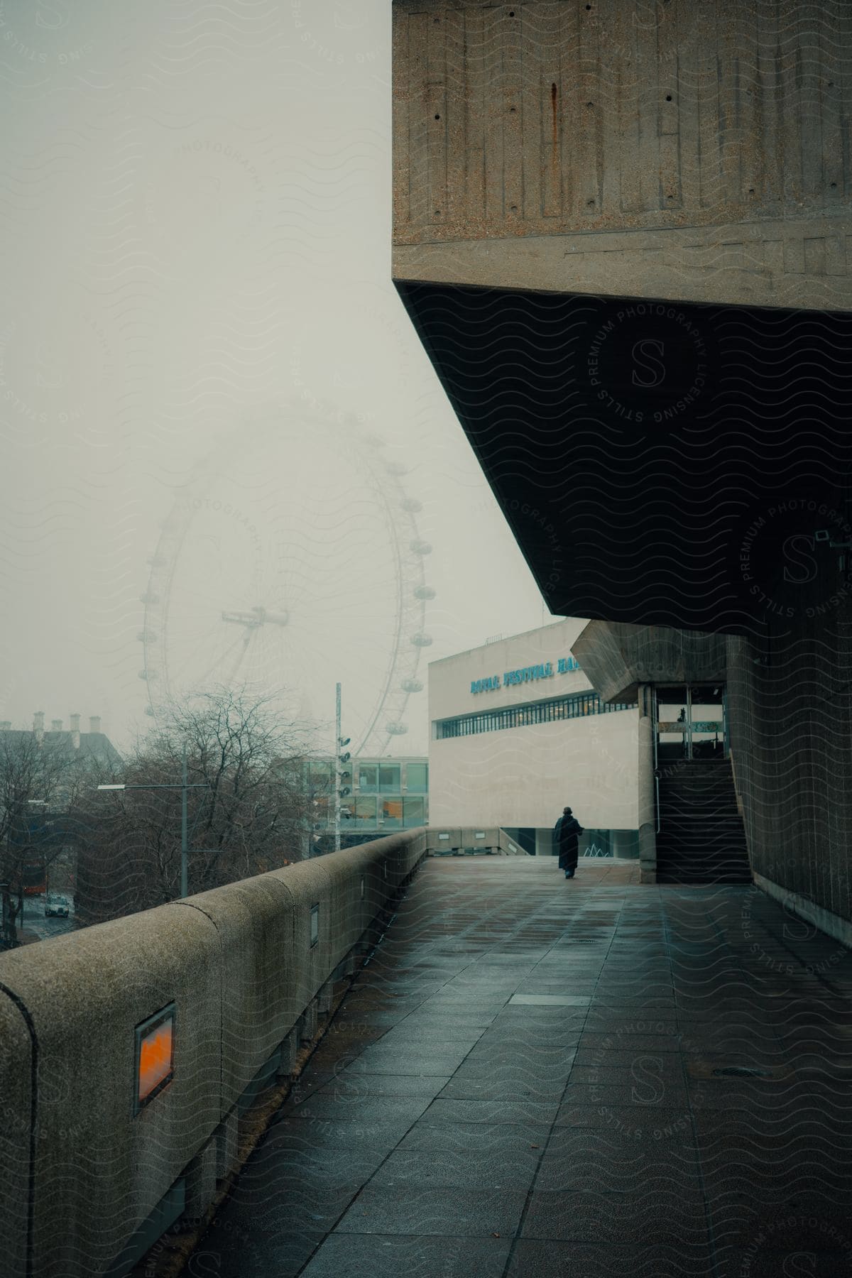 External corridor of the National Theater on a foggy day with a Ferris wheel in the background.
