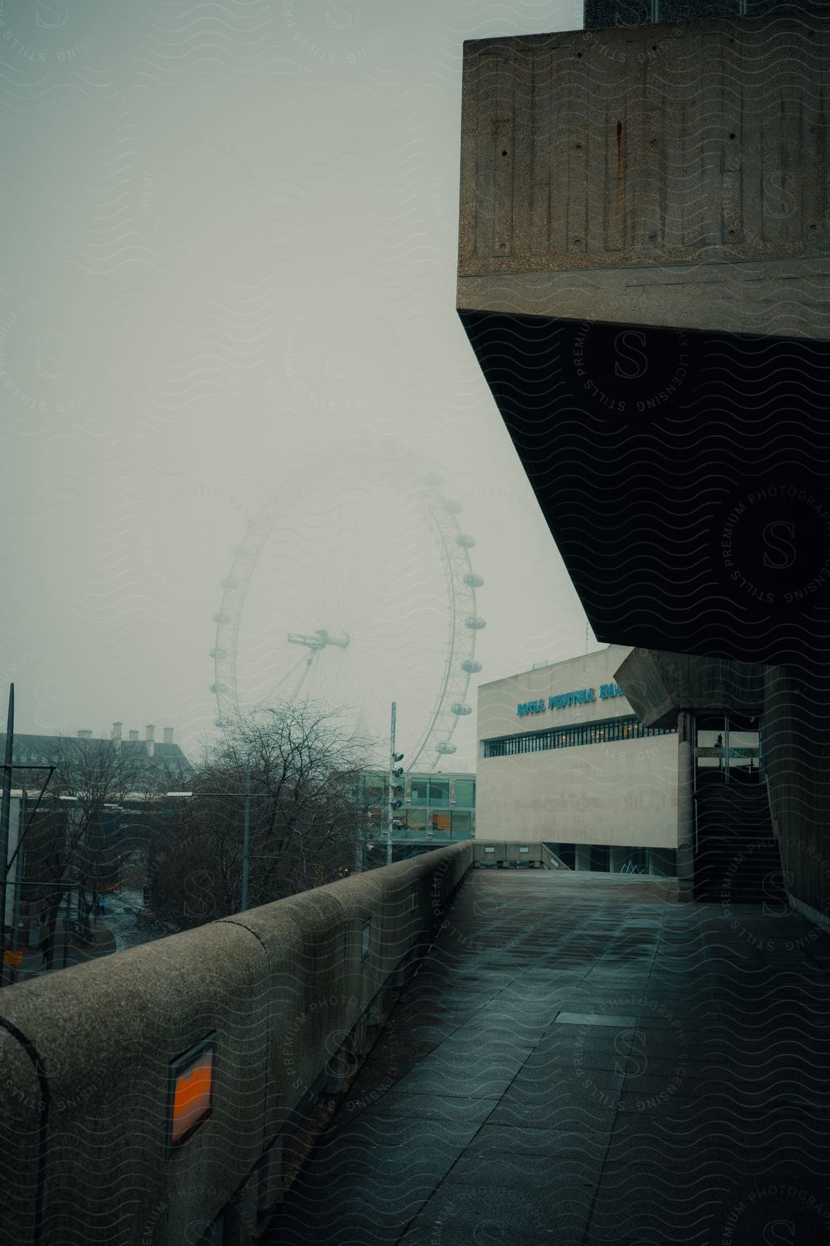 Walkway next to a building and a Ferris wheel high above buildings in the distance