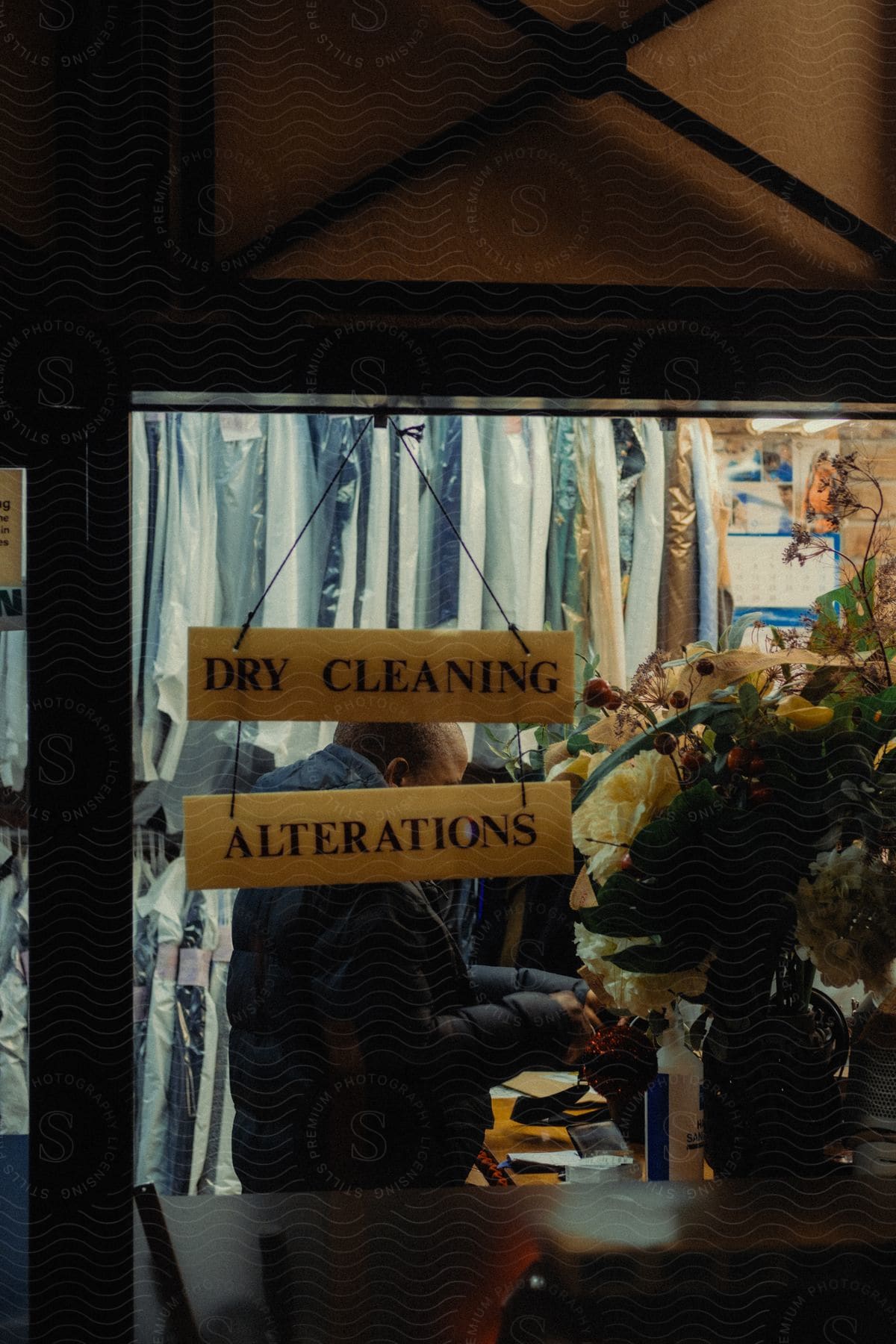 Through the window of a store, you can see the inside of an establishment that offers dry cleaning services and adjustments.