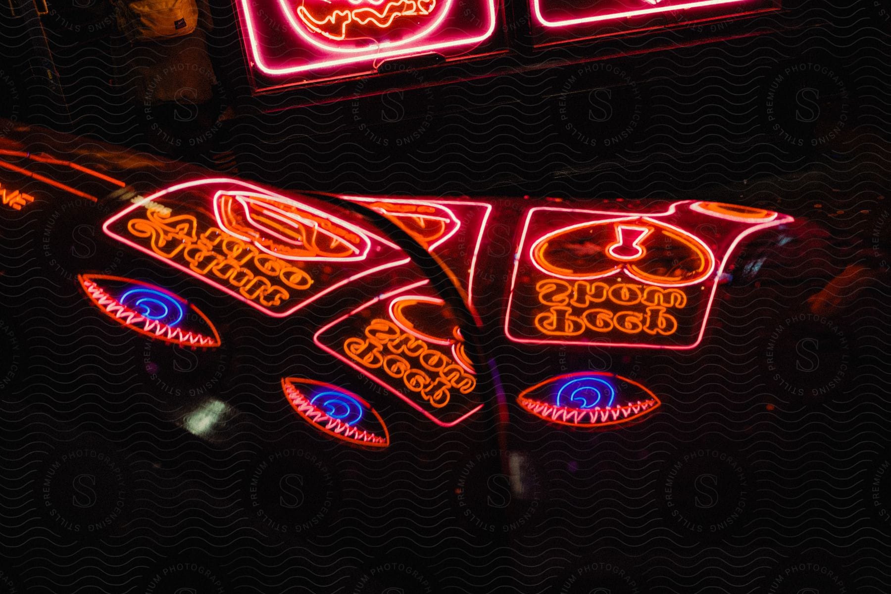 Neon signs reflect off the hood of a car.