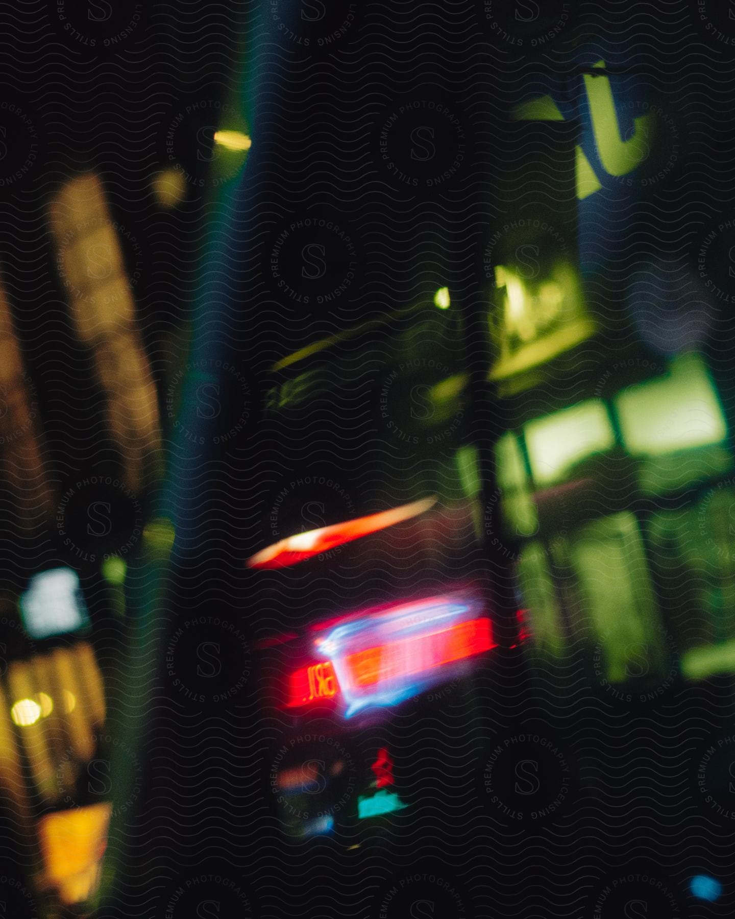 Blurred image of buildings lit up at night in neon across the city.