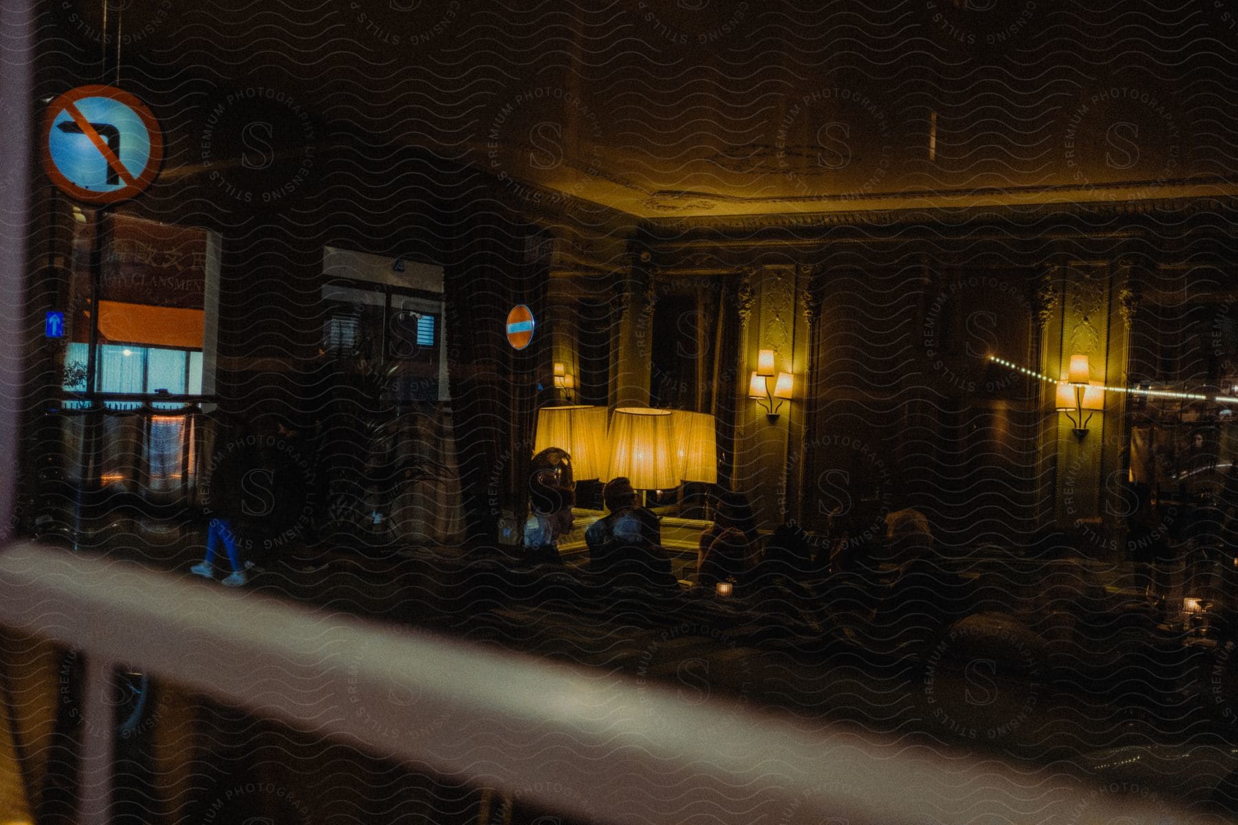 A restaurant with dim lighting where guests sit around tables, attended to by staff.