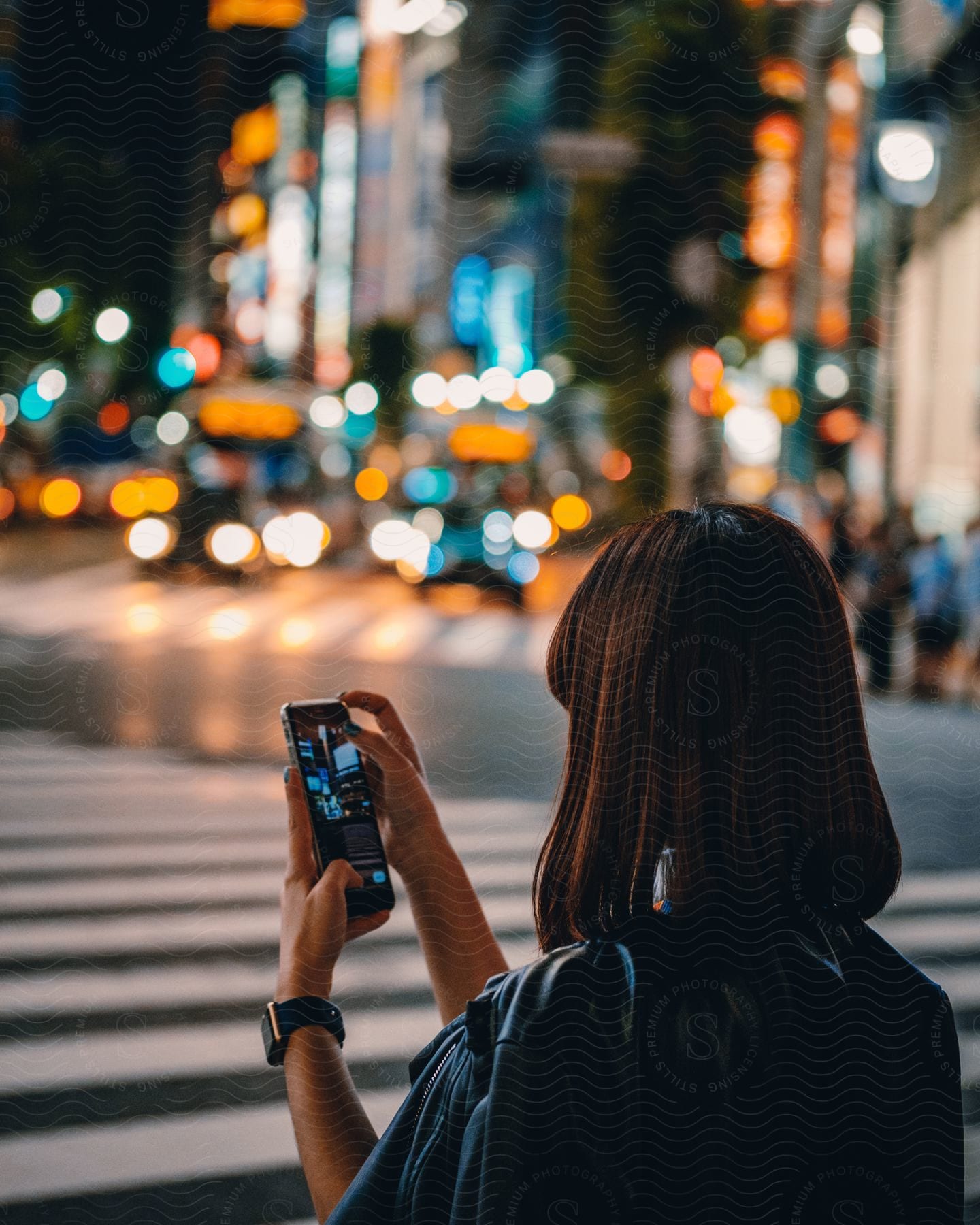 Stock photo of an asian woman in a big city taking a picture with her phone.
