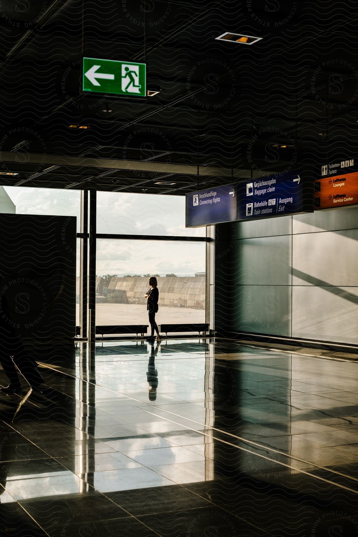 A woman looks out the window in the lobby of an airport.