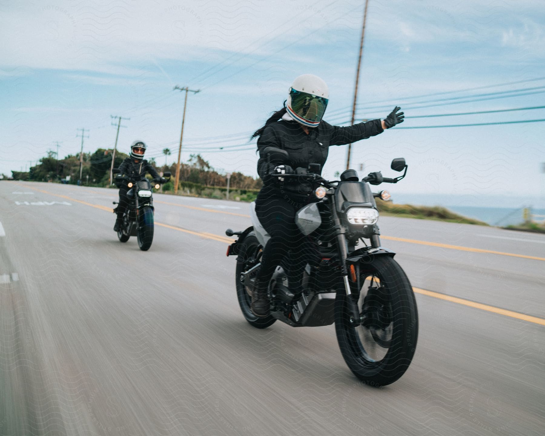 Two adults ride motorcycles on the highway.