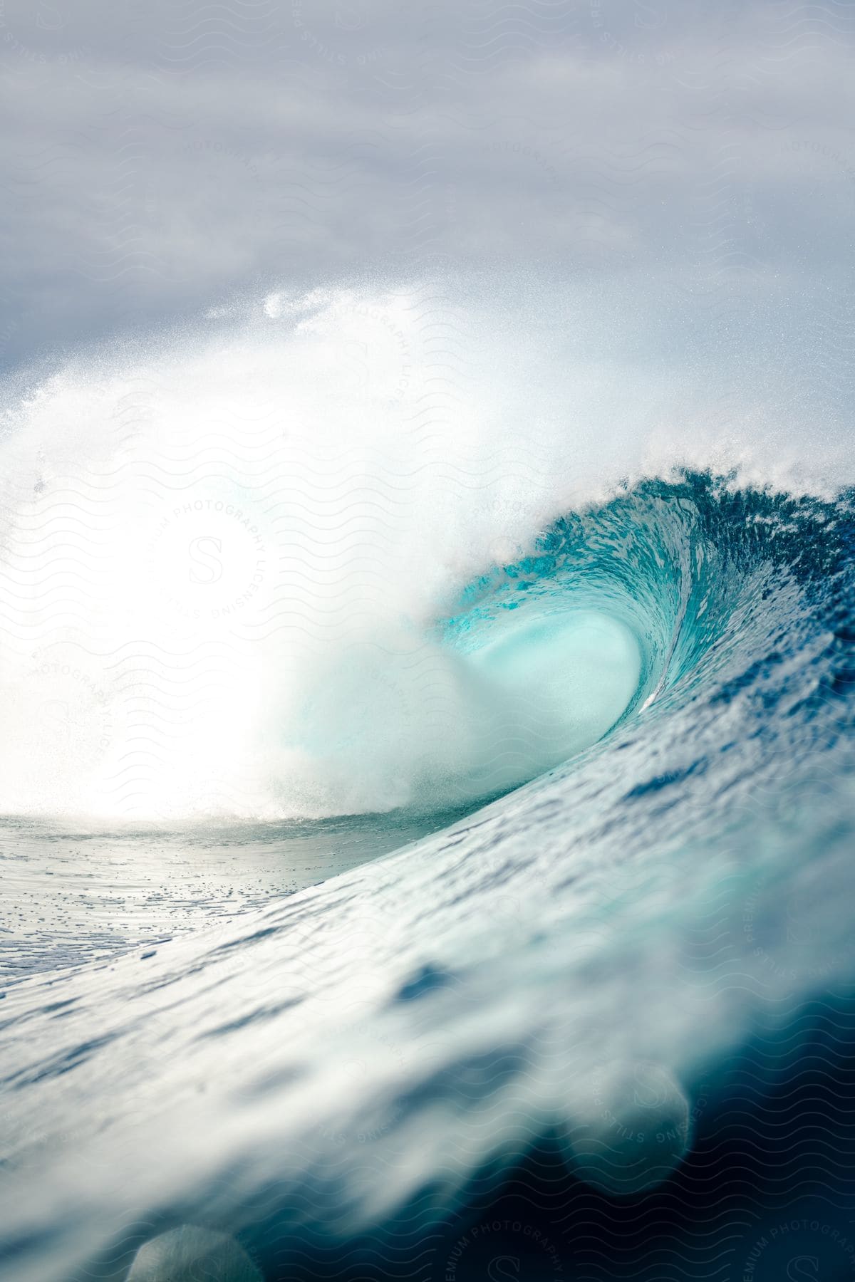 Strong, crystal clear wave breaking in the middle of the sea on a cloudy day.