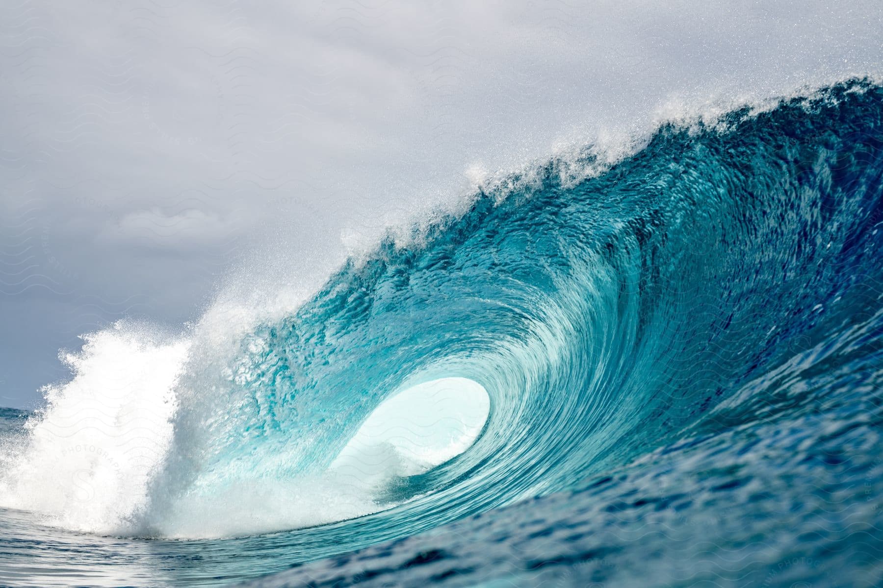 Deep in the ocean, a massive wave forms, creating a circular drop on a sunny day.