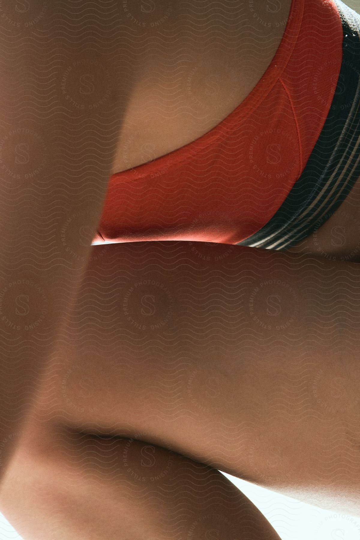 This is a close-up image capturing the play of light and shadow on a person's torso, emphasizing the form and texture of the skin and clothing.