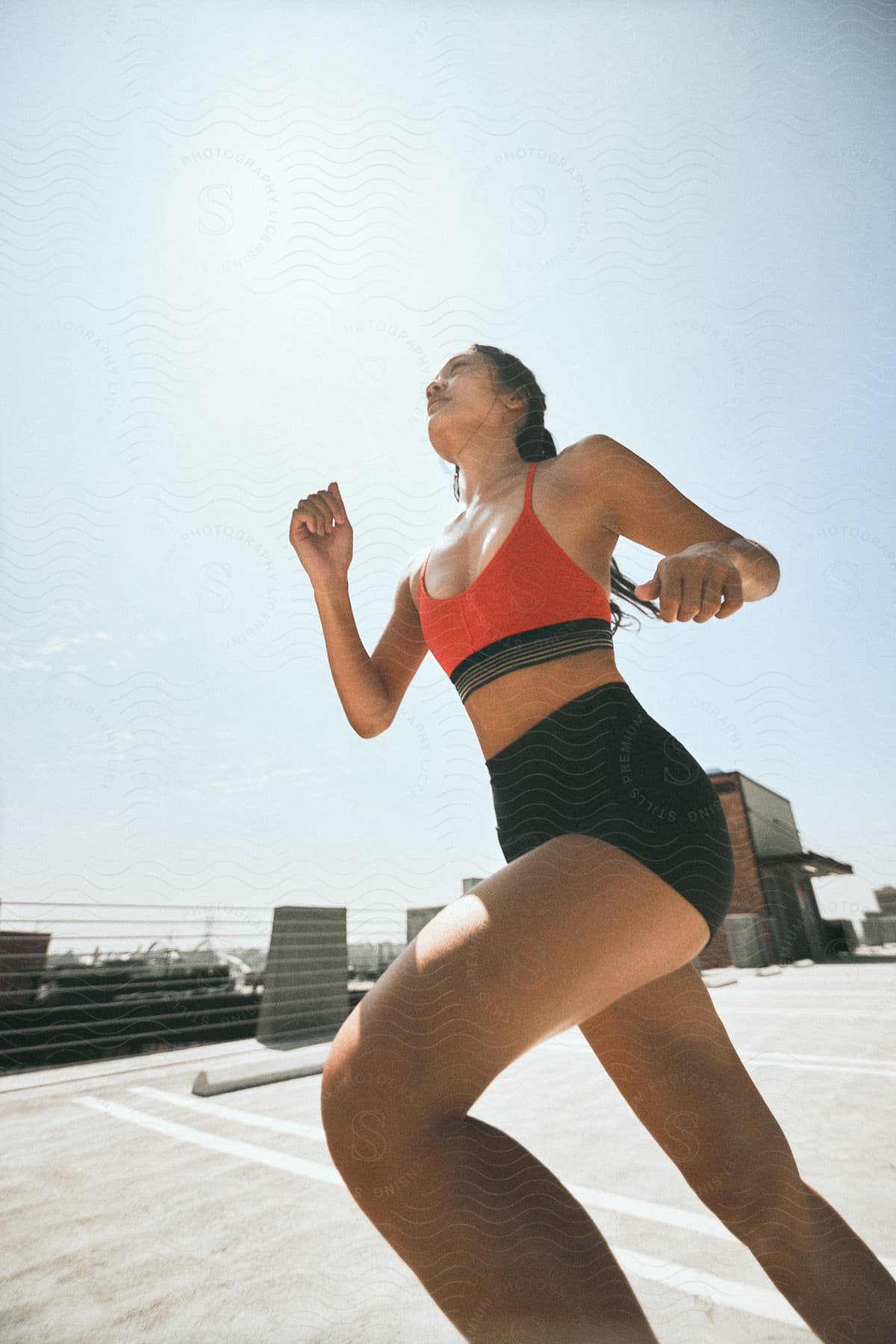 Woman in fitness clothes performing aerobic exercises outdoors during the day