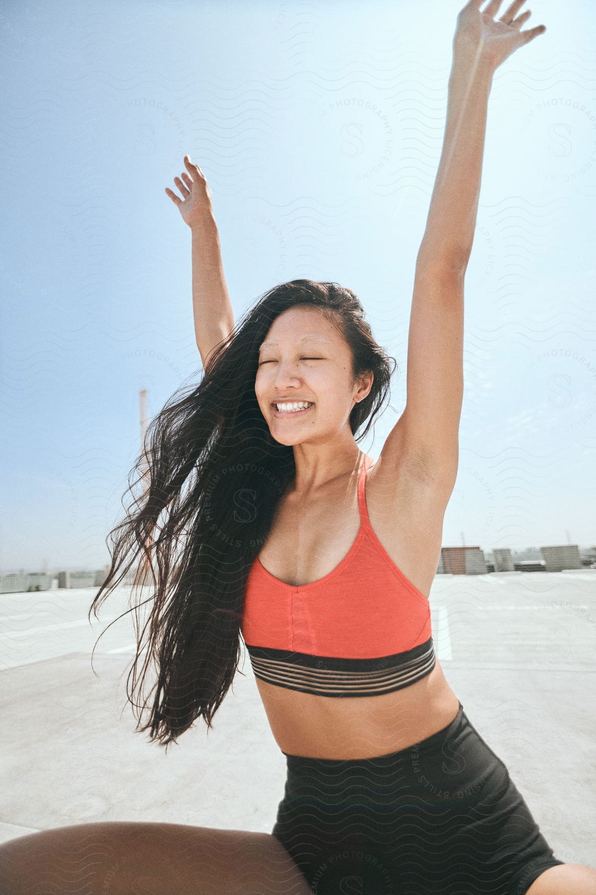 A smiling woman in yoga position outdoors.