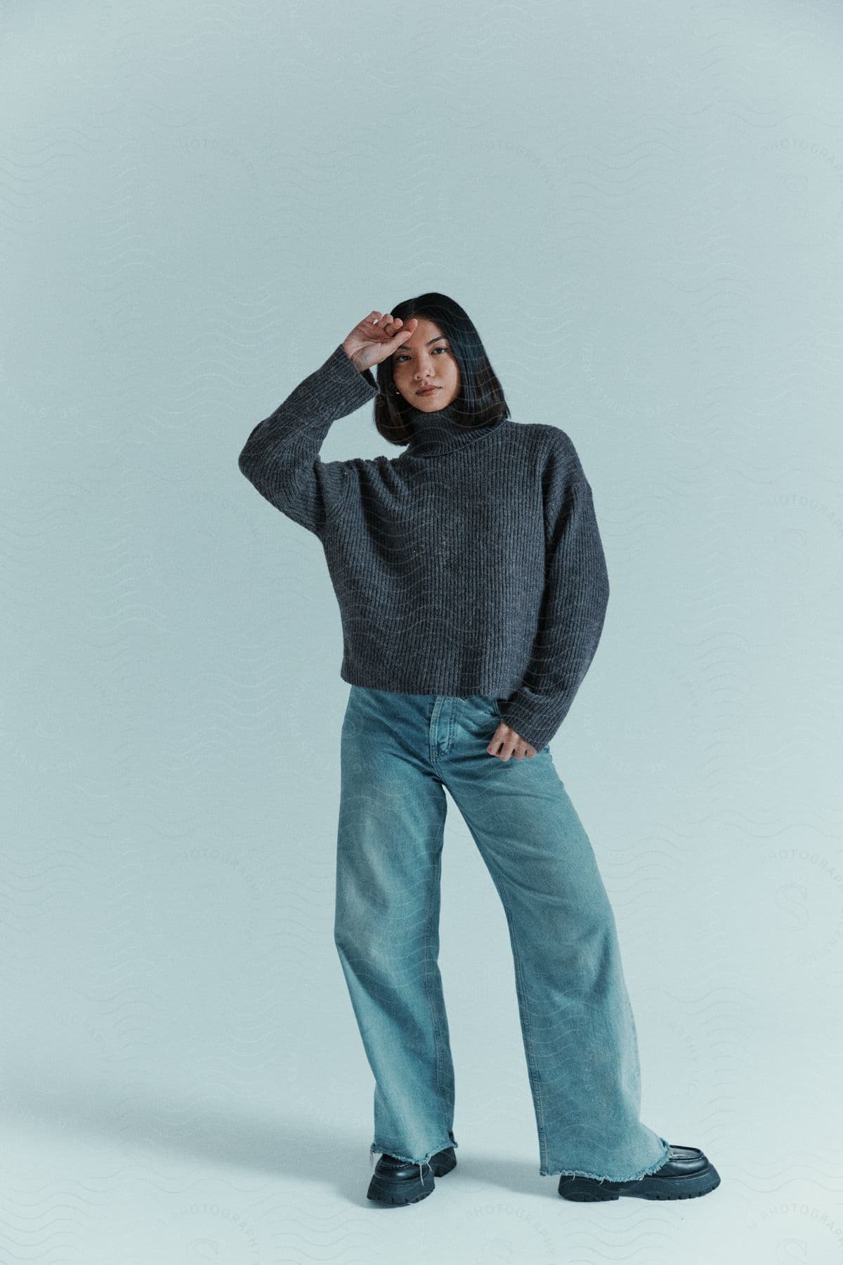 Young woman wearing blue jeans and a sweater is standing with one hand on her forehead