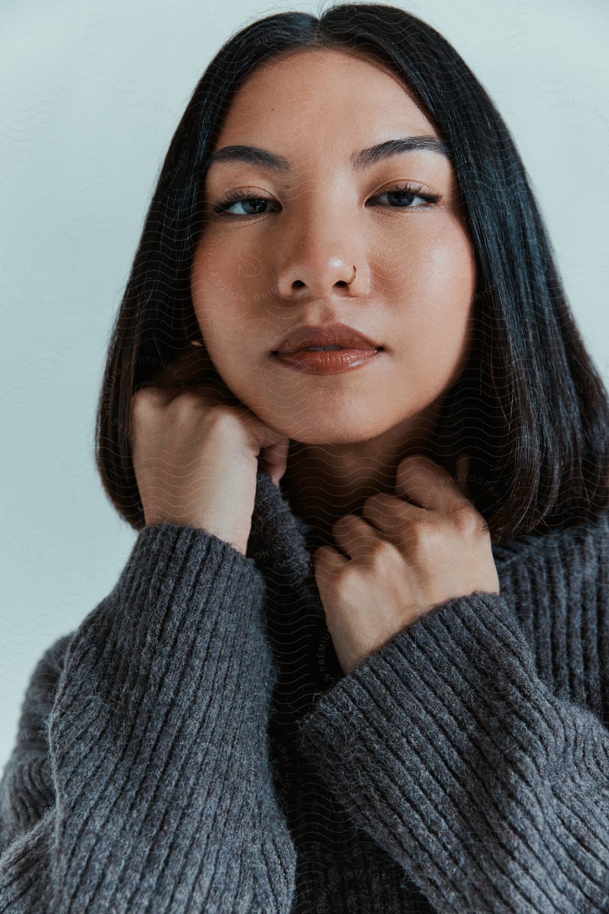 Portrait of a young woman holding a gray sweater that is blowing.