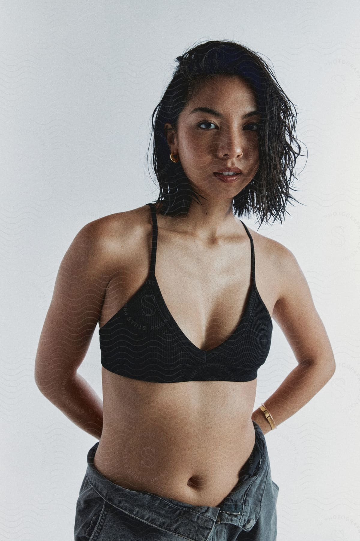 A young Asian woman poses in a black sports bra and jeans.