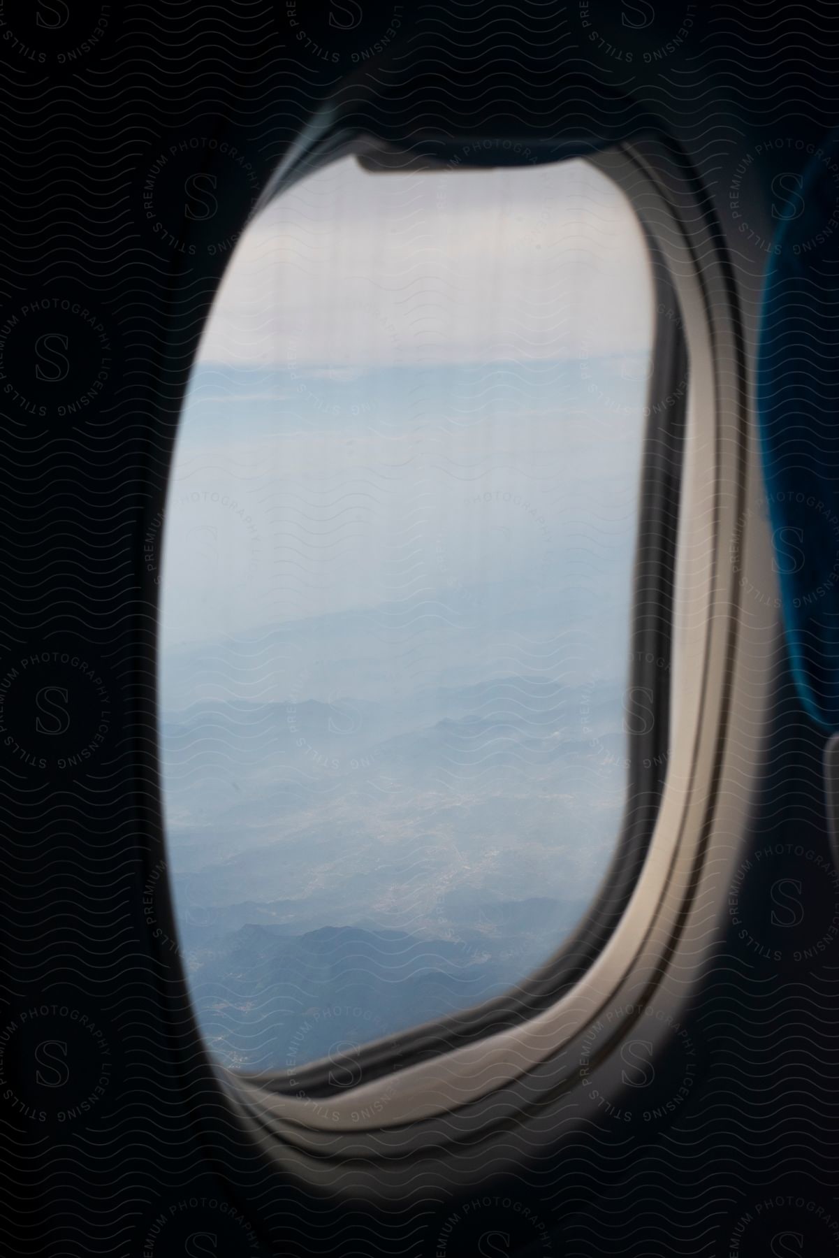 Close-up of the window of an airplane flying over mountains.