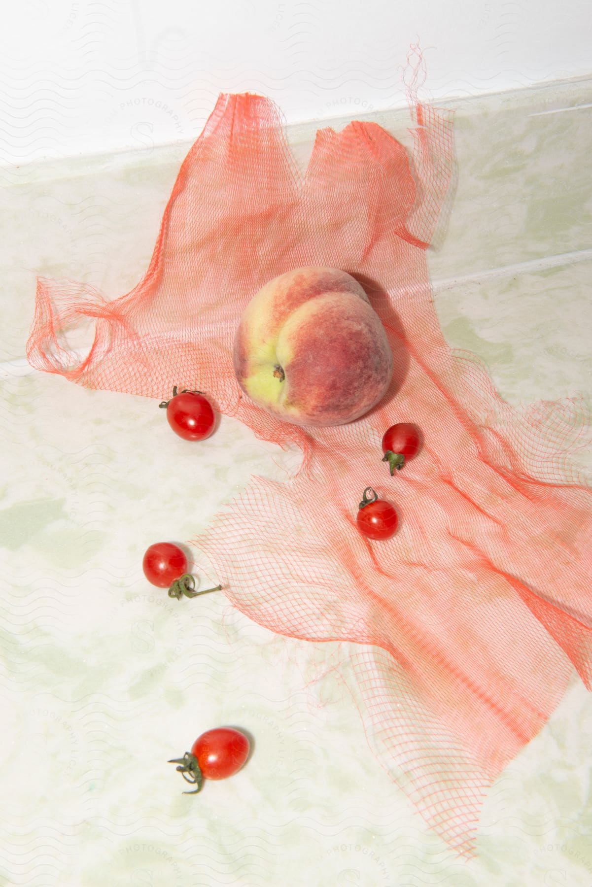and tomatoes are on a table with a net on it and a piece of cloth on the floor