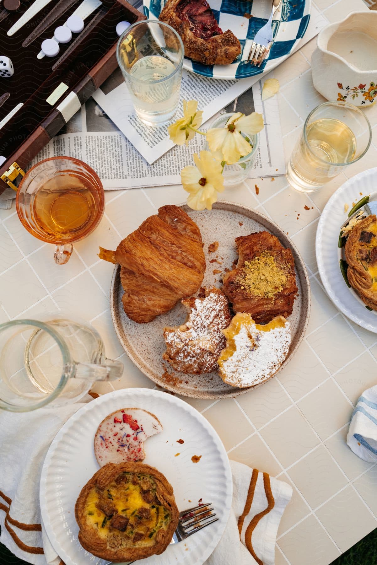 A table is set with glasses of drinks and brunch items such as bread and cake served on plates.