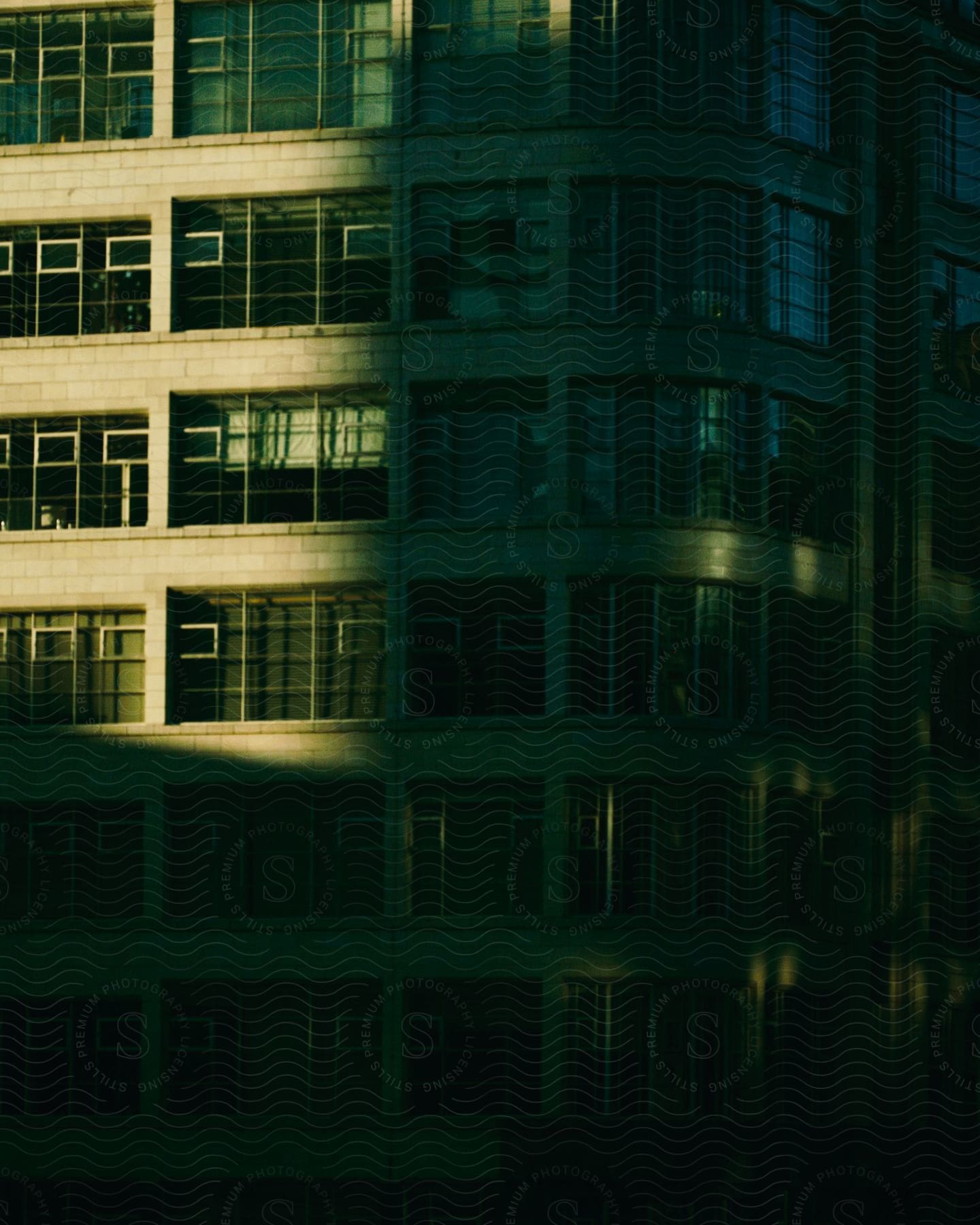 A modern building with lots of windows, illuminated by soft sunlight. The clean lines and geometric patterns created by the windows highlight the architecture.