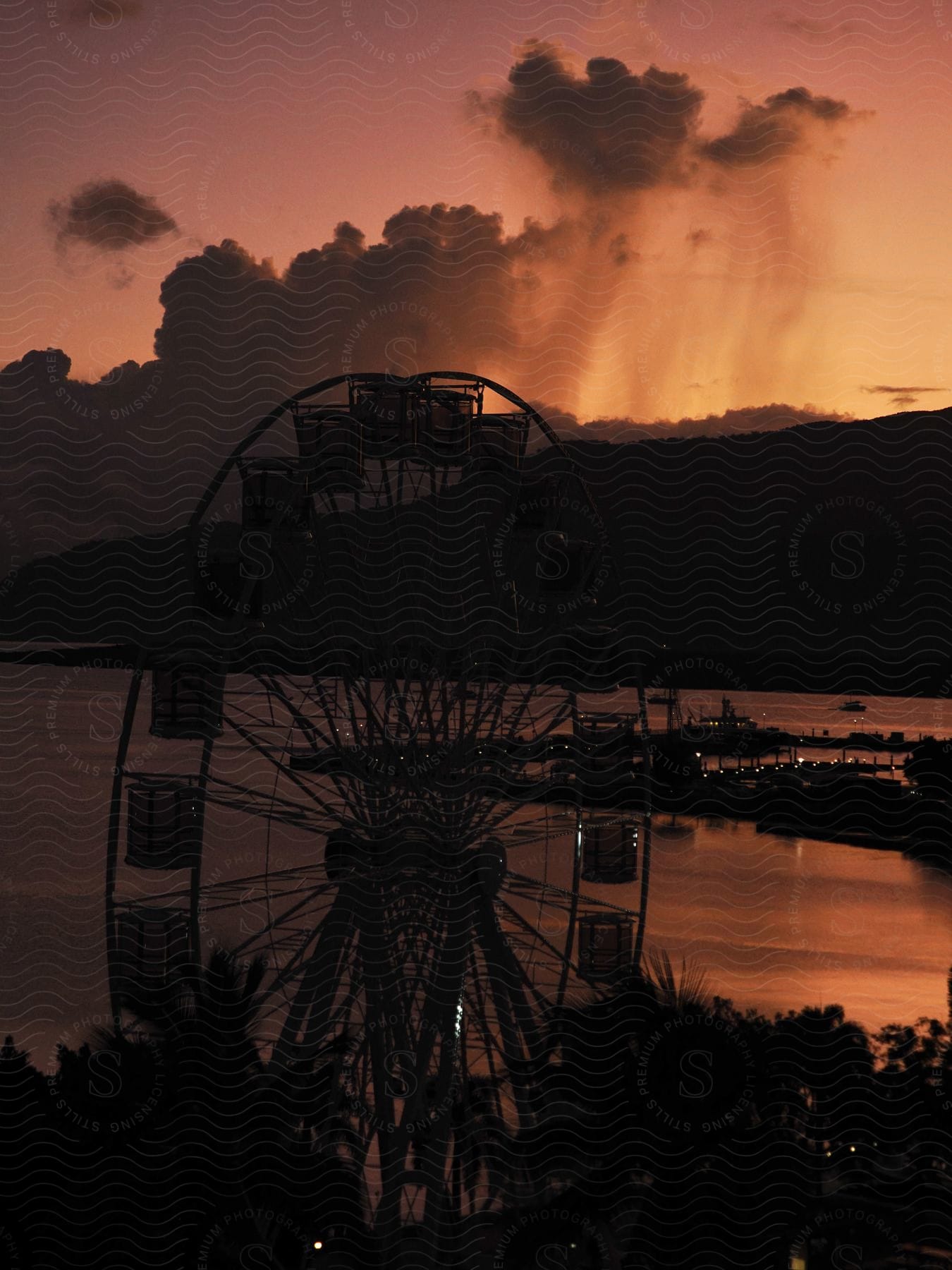 A Ferris wheel rises over a coastal town at dusk.