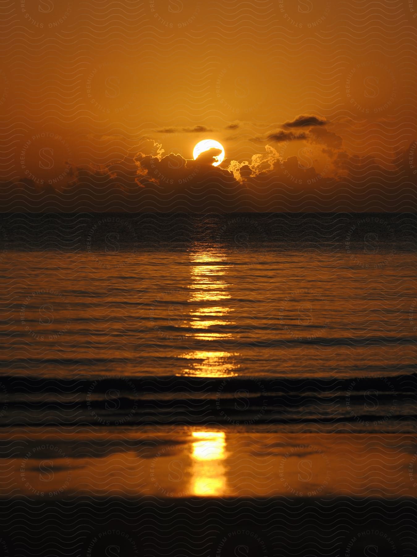 Paradisiacal scenery of sunrise on the horizon reflecting the calm sea.