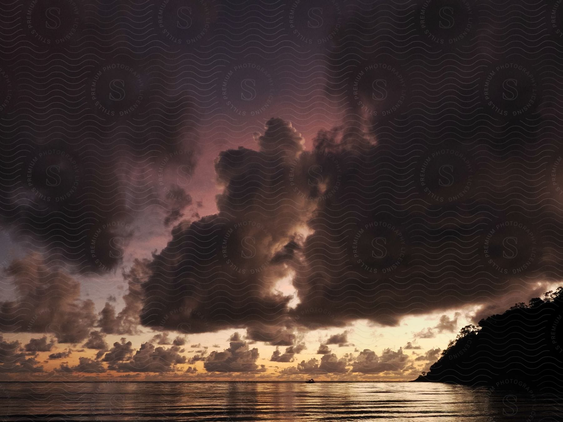 A Large Cloud Fills The Sunset Sky Over A Lake, With A Tree-covered Mountain Island Silhouetted On The Right