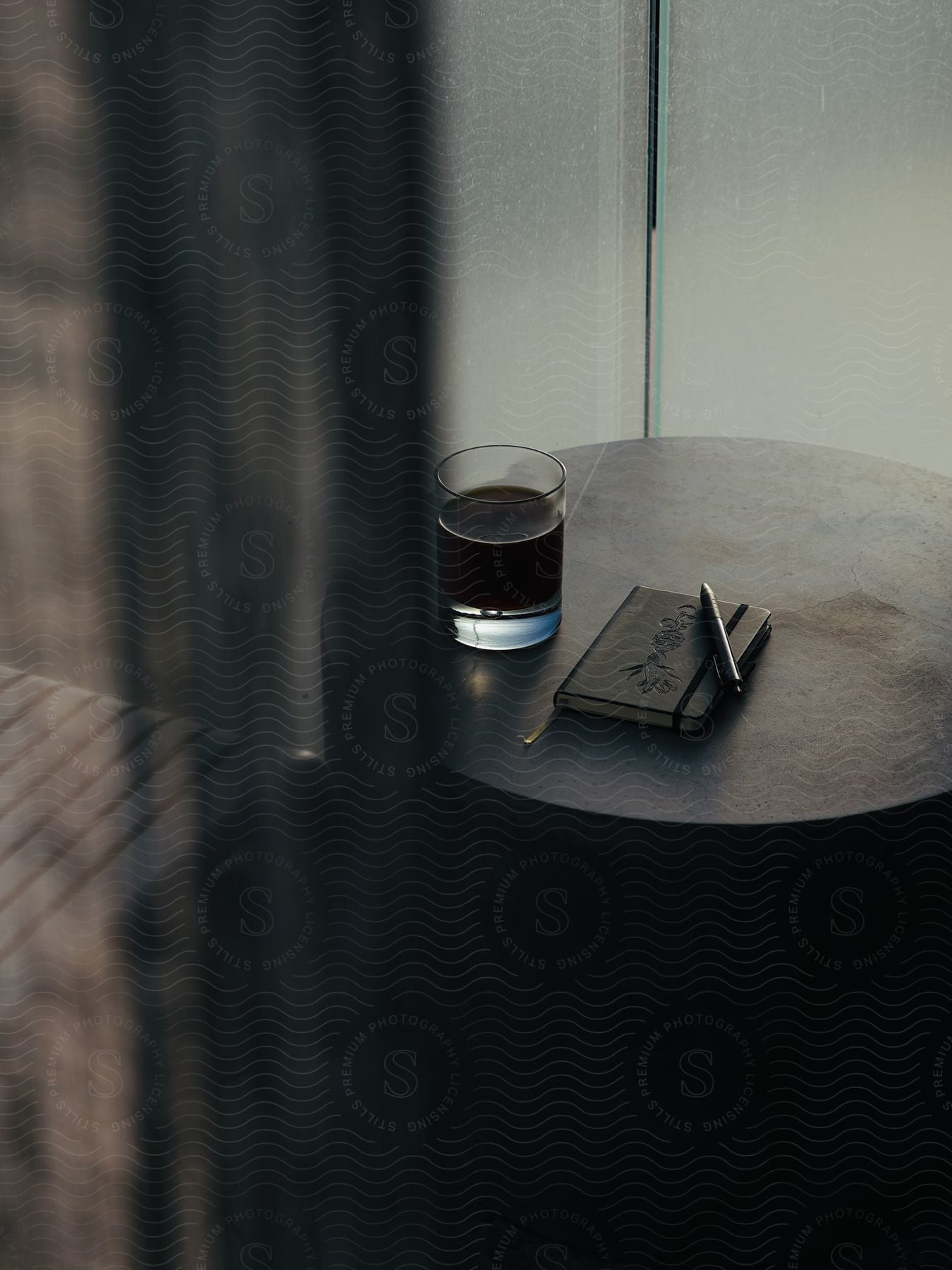 Glass cup with a drink next to a card with pen on a counter in an indoor environment.