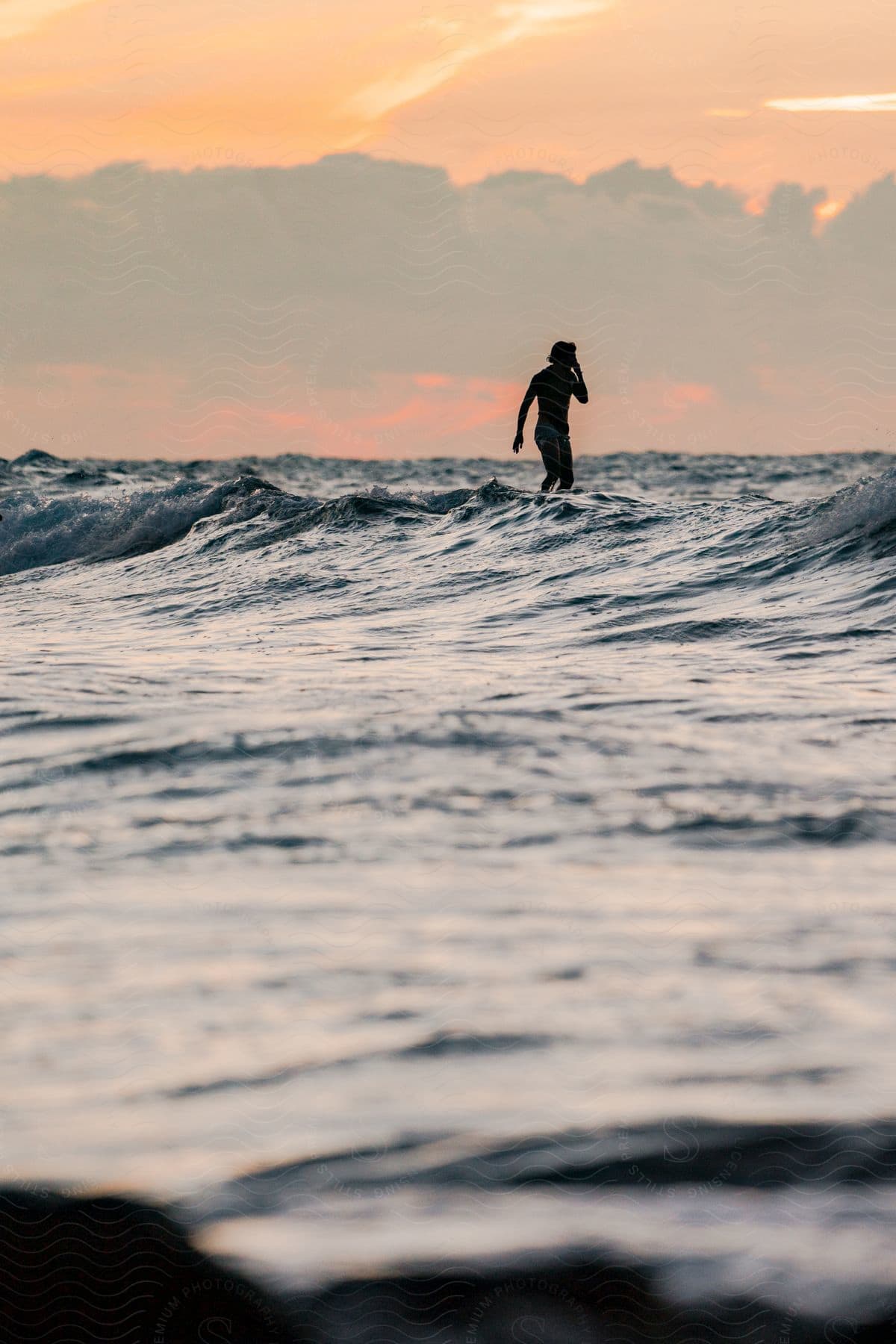 A man standing on a surfboard at sunset