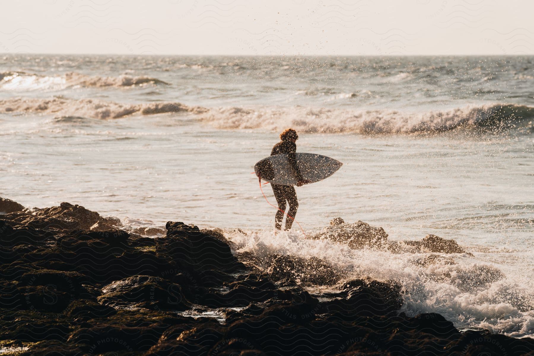 A person with a surfboard heading into the ocean.