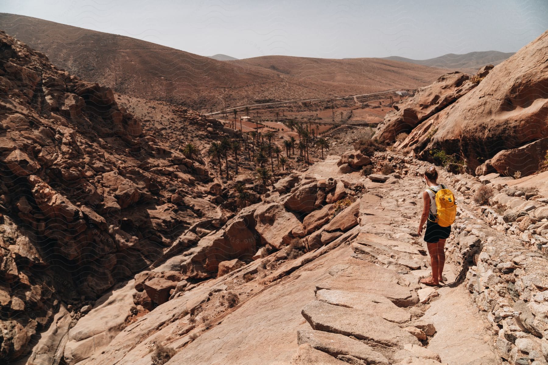 A hiker looks at buildings in a remote desert area