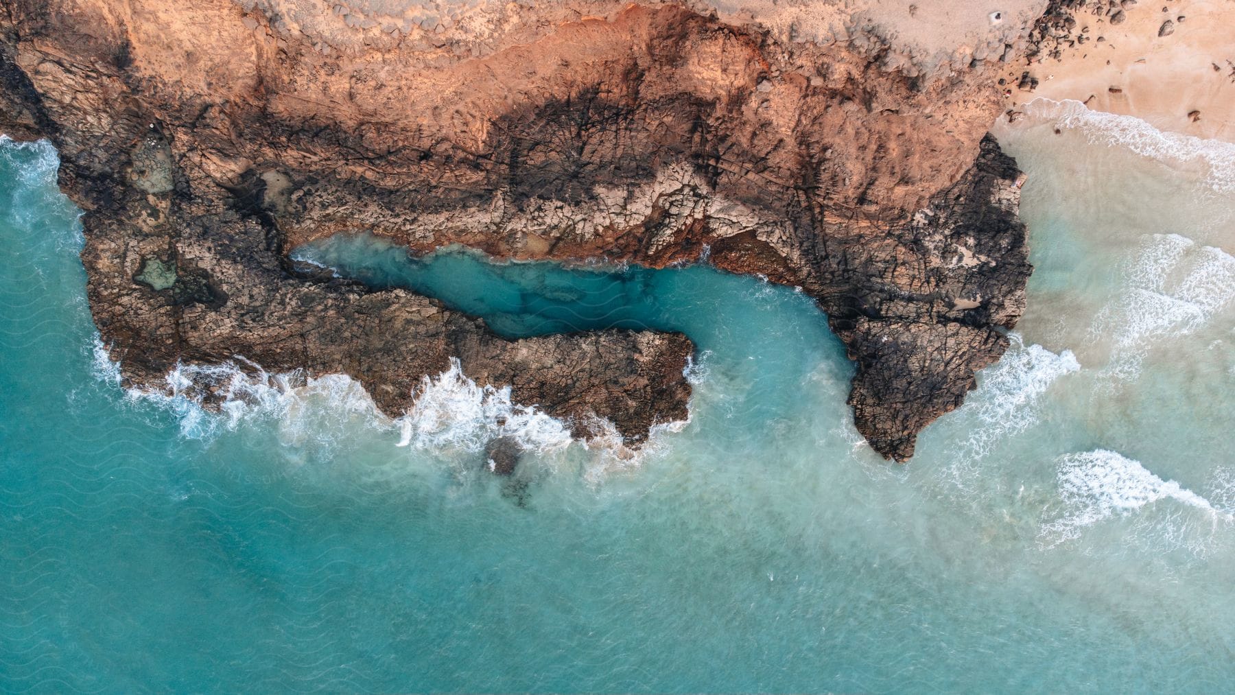 Waves crash into a rocky extension of coastal cliffs