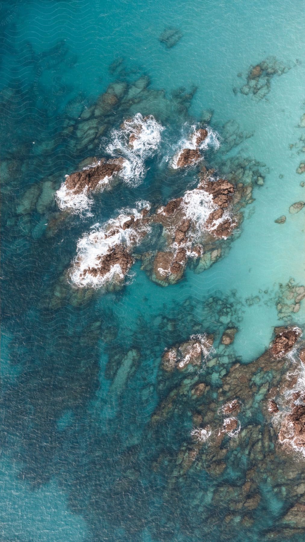 An aerial view of a scenic waterway with rocks dotting the crystal-clear water