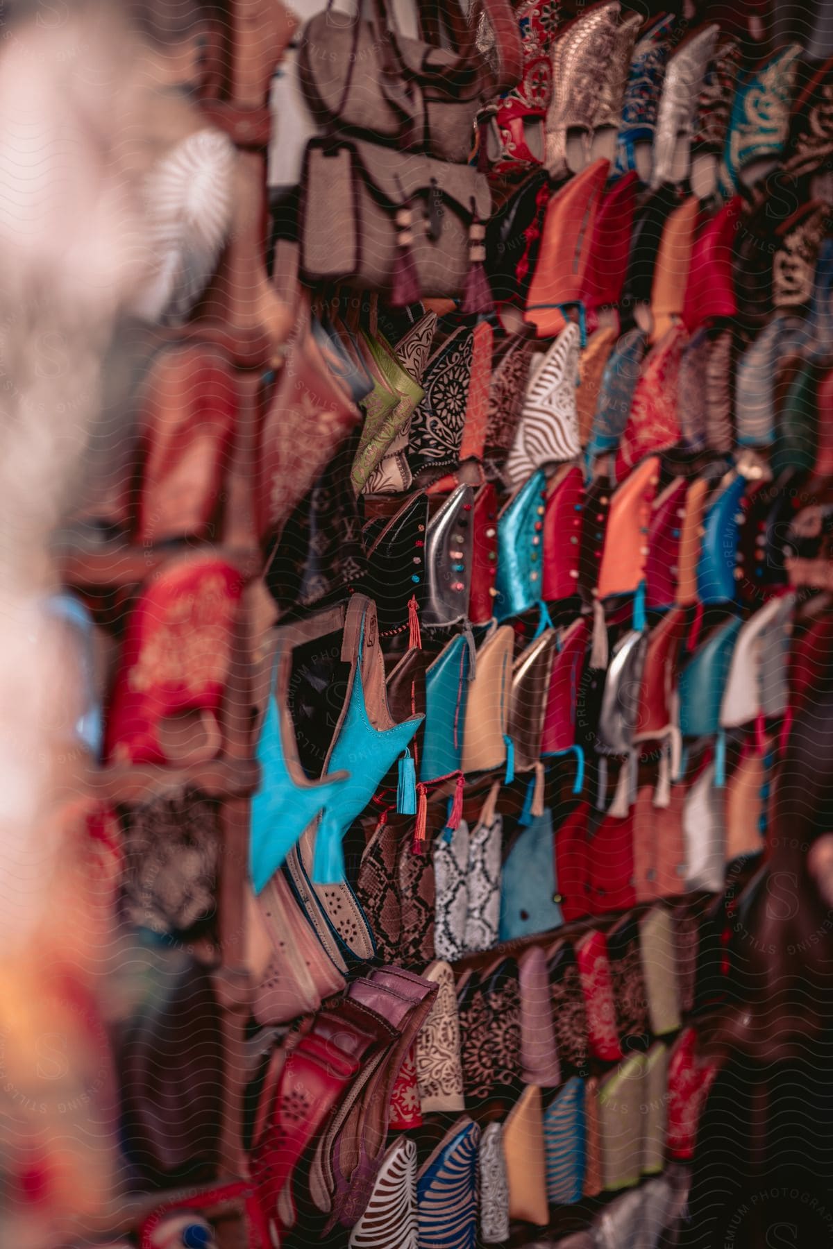 A wall of shoes and sandals creates a colorful display, with footwear of all styles hanging from hooks or shelves.