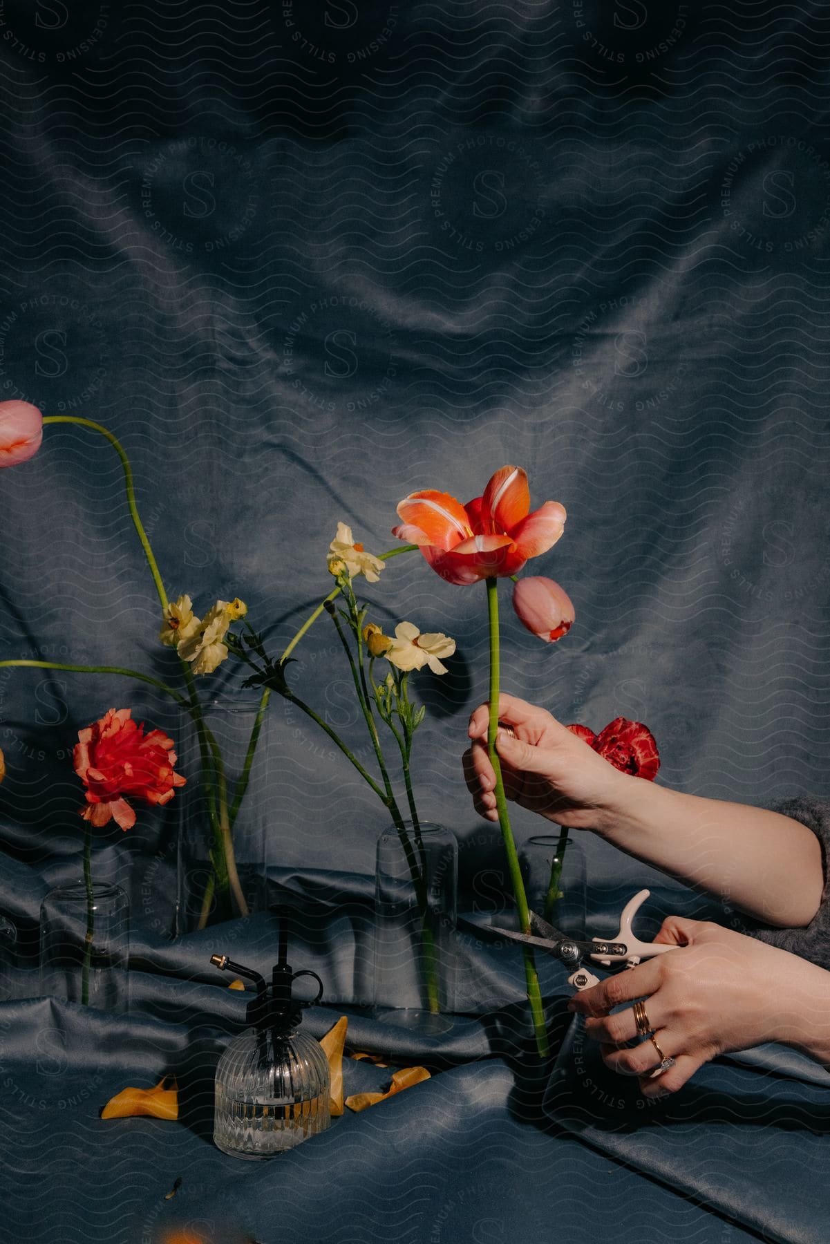 A woman cuts a stem on a large flower in a flower arrangement