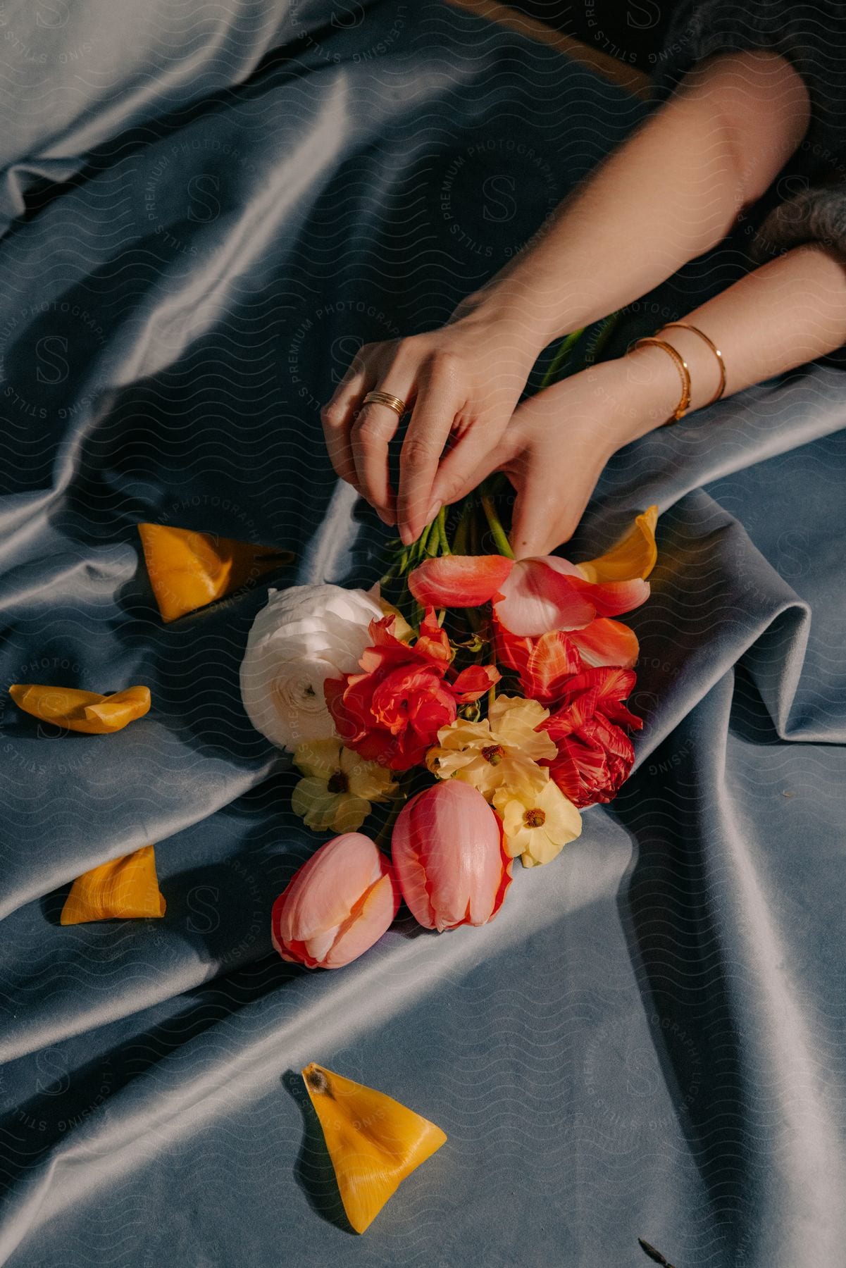 A photographer arranging flowers on a gray satin backdrop