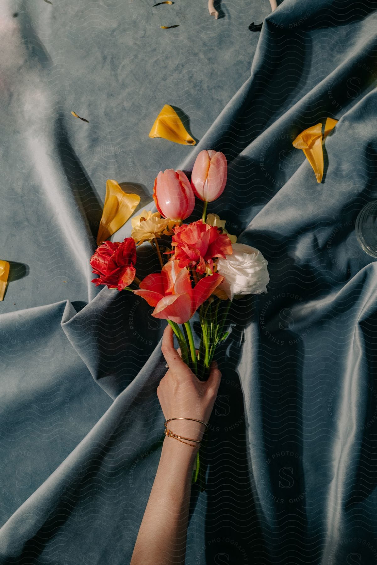 A human hand holding a bouquet of some flowers on top of a black cloth