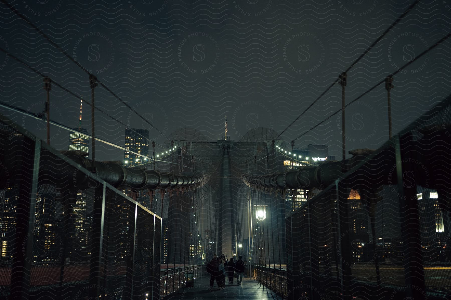 View of the Brooklyn Bridge with skyscrapers in the background in a metropolis at night.