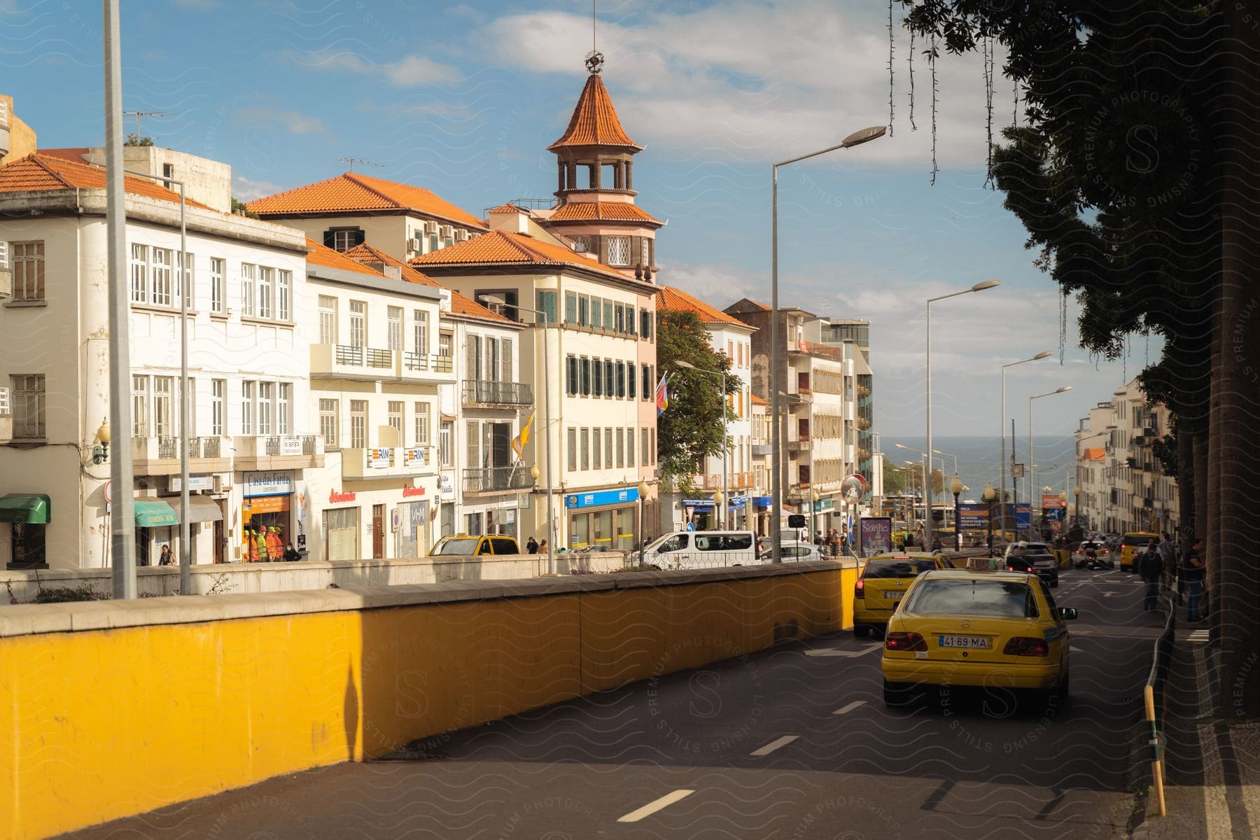 Rua 5 de Outubro in Portugal with vehicle traffic and the sea in the background during the day.