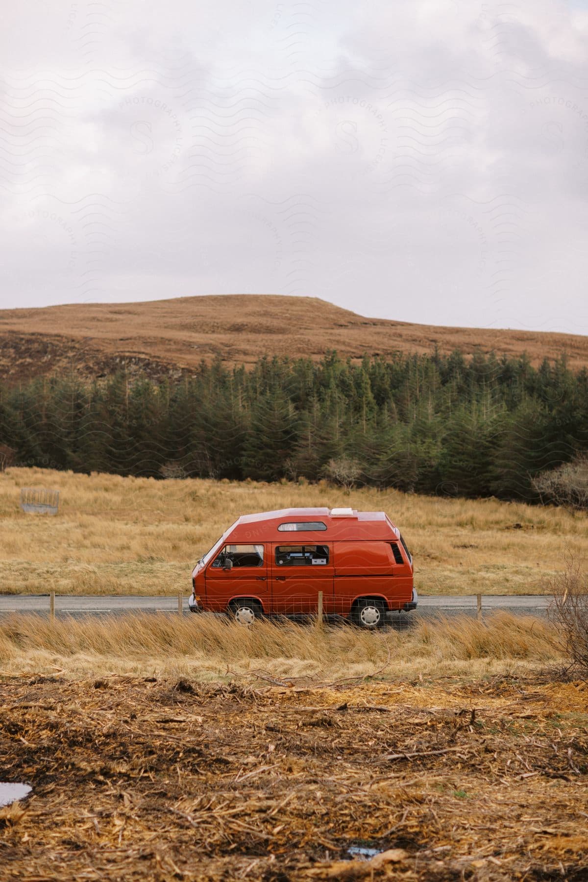 A bus sitting out on a road near a forest