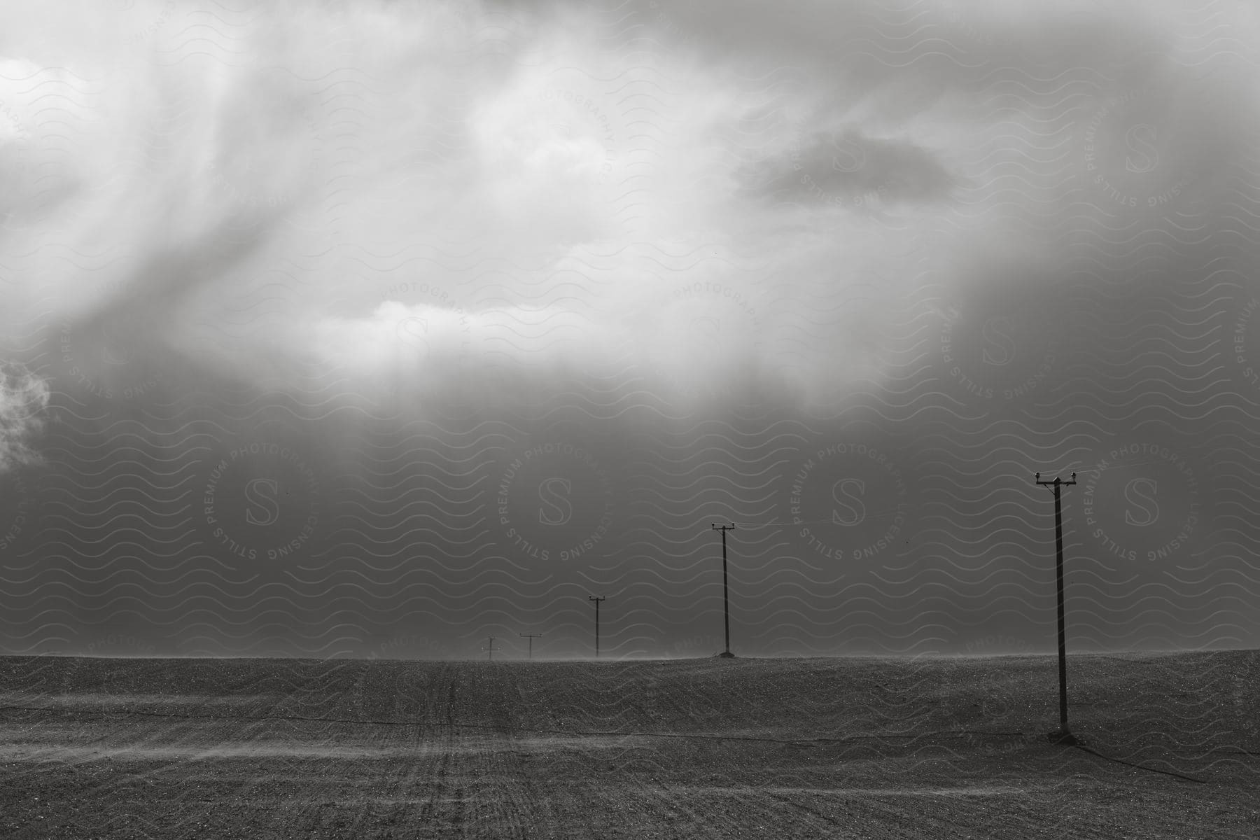 Panorama of an agricultural field with power transmission poles on a cloudy day