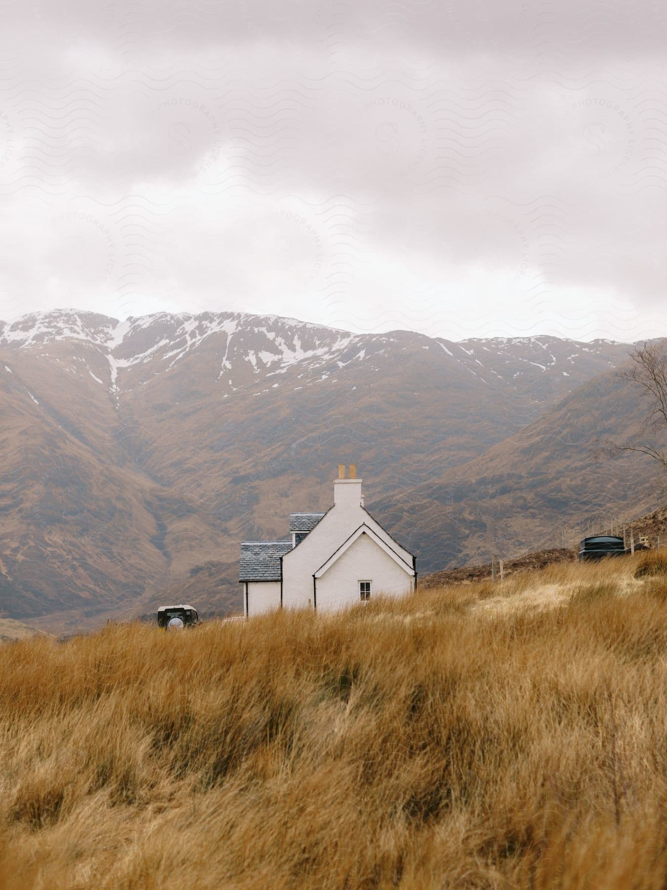 House on a hill with mountains around on a cloudy winter day.