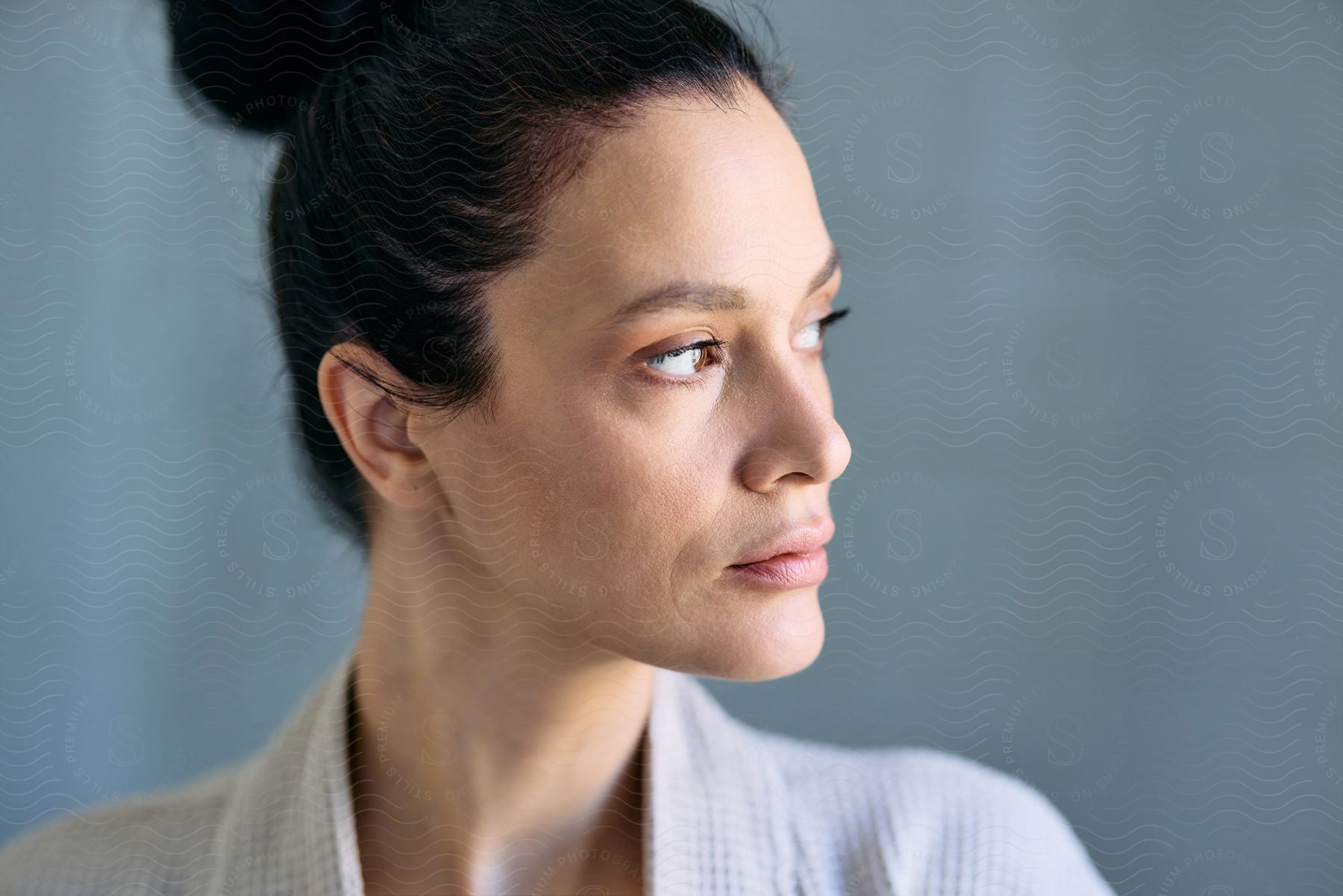 A profile view of a woman with a bun hairstyle, looking thoughtfully to the side.