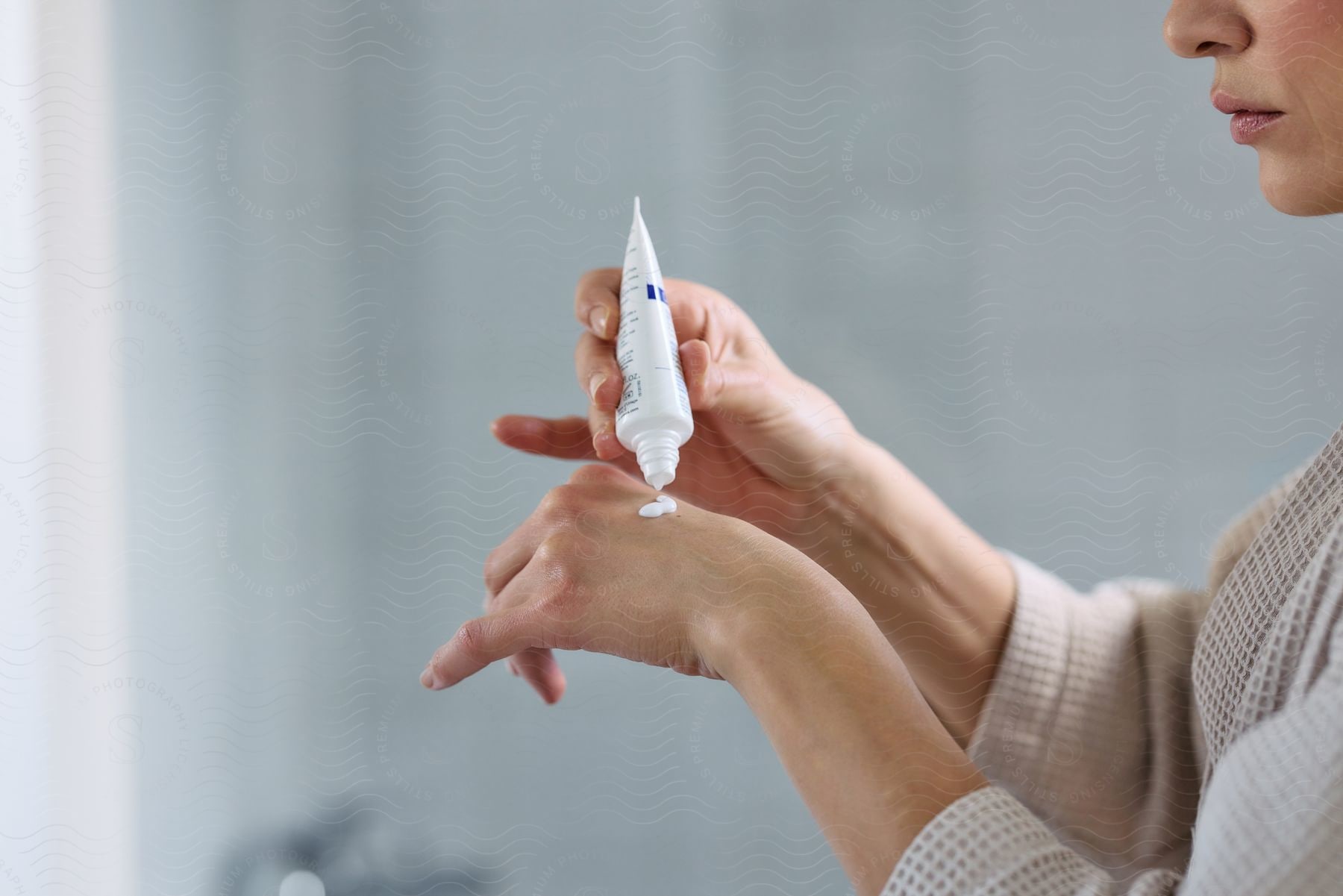 A Woman Wearing A Sweater Applies Hand Cream