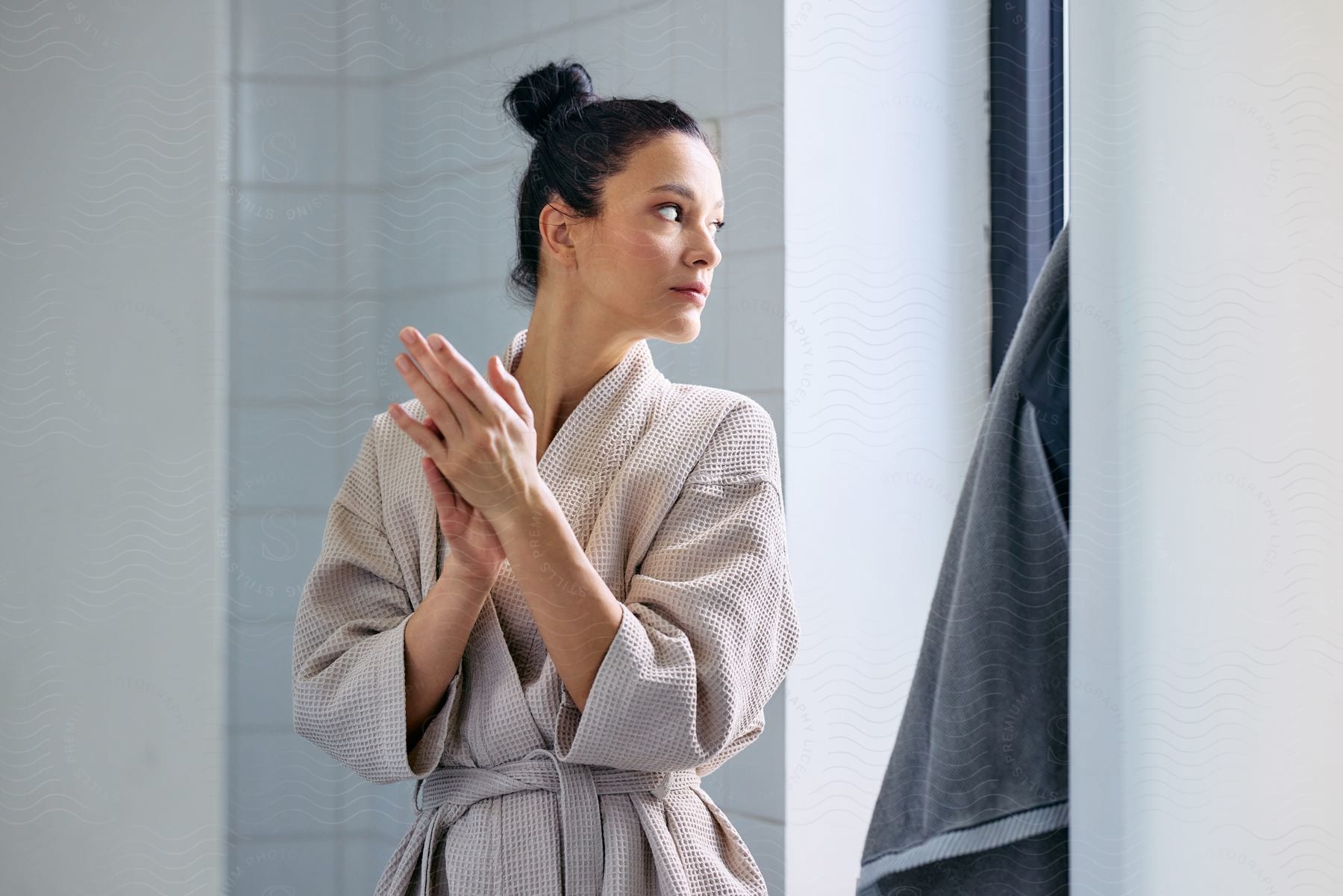 A woman rubs her hands together while wearing a bathrobe.