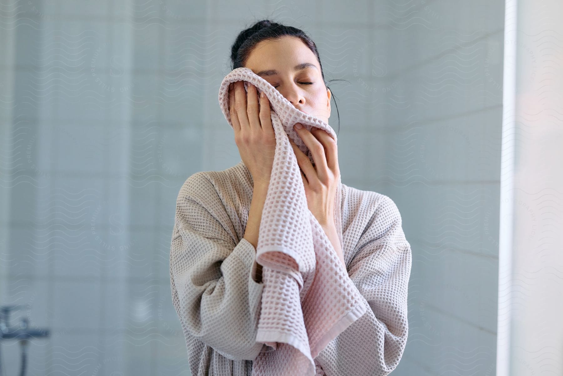 A young woman is wiping her face with a towel full of holes