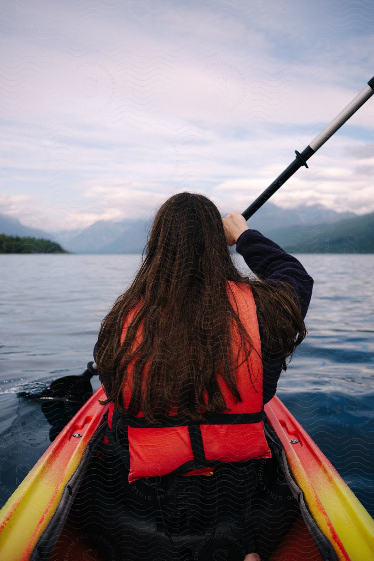 A woman paddling a canoe outdoors on a lake