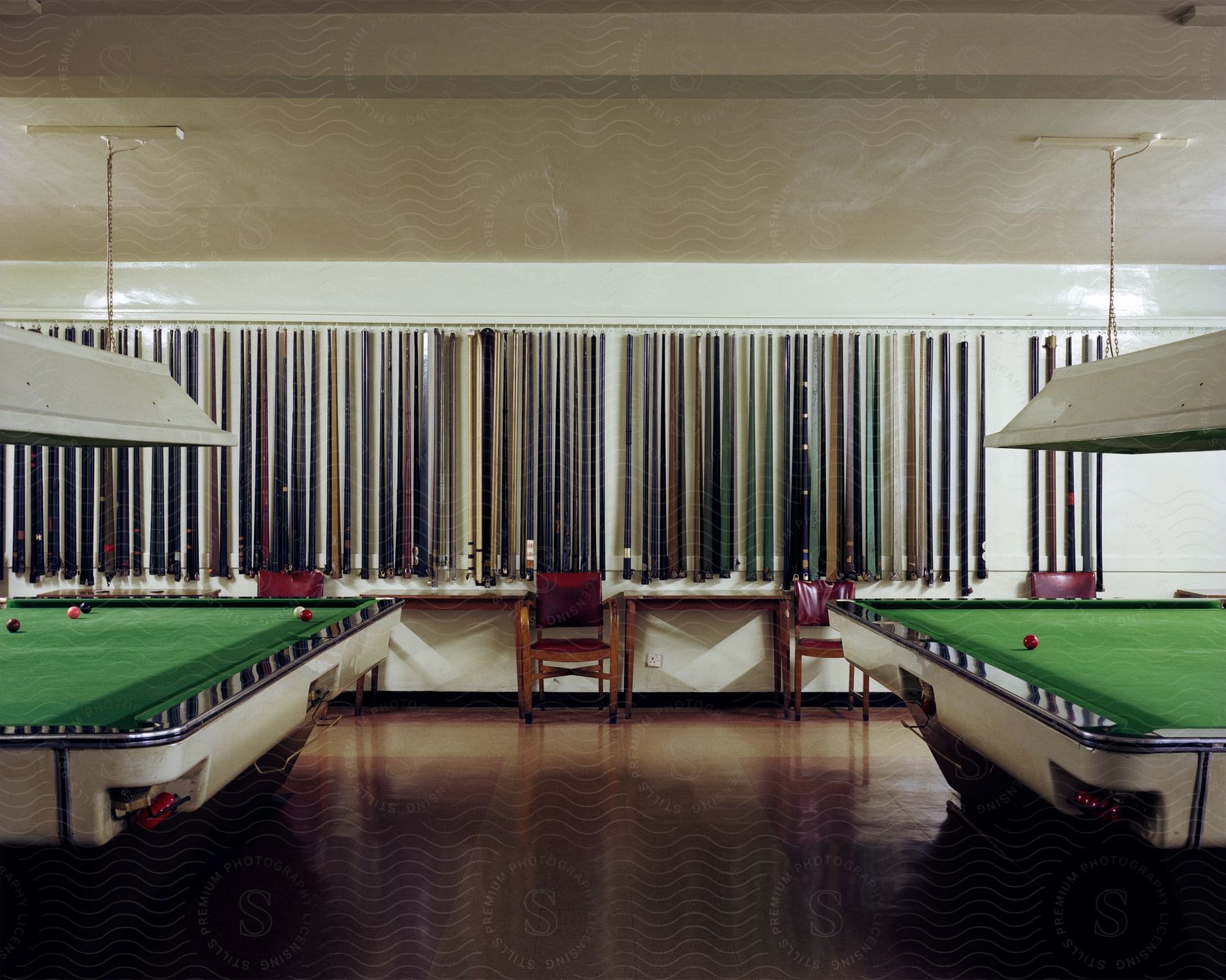 A pool table game room with pool sticks on the wall