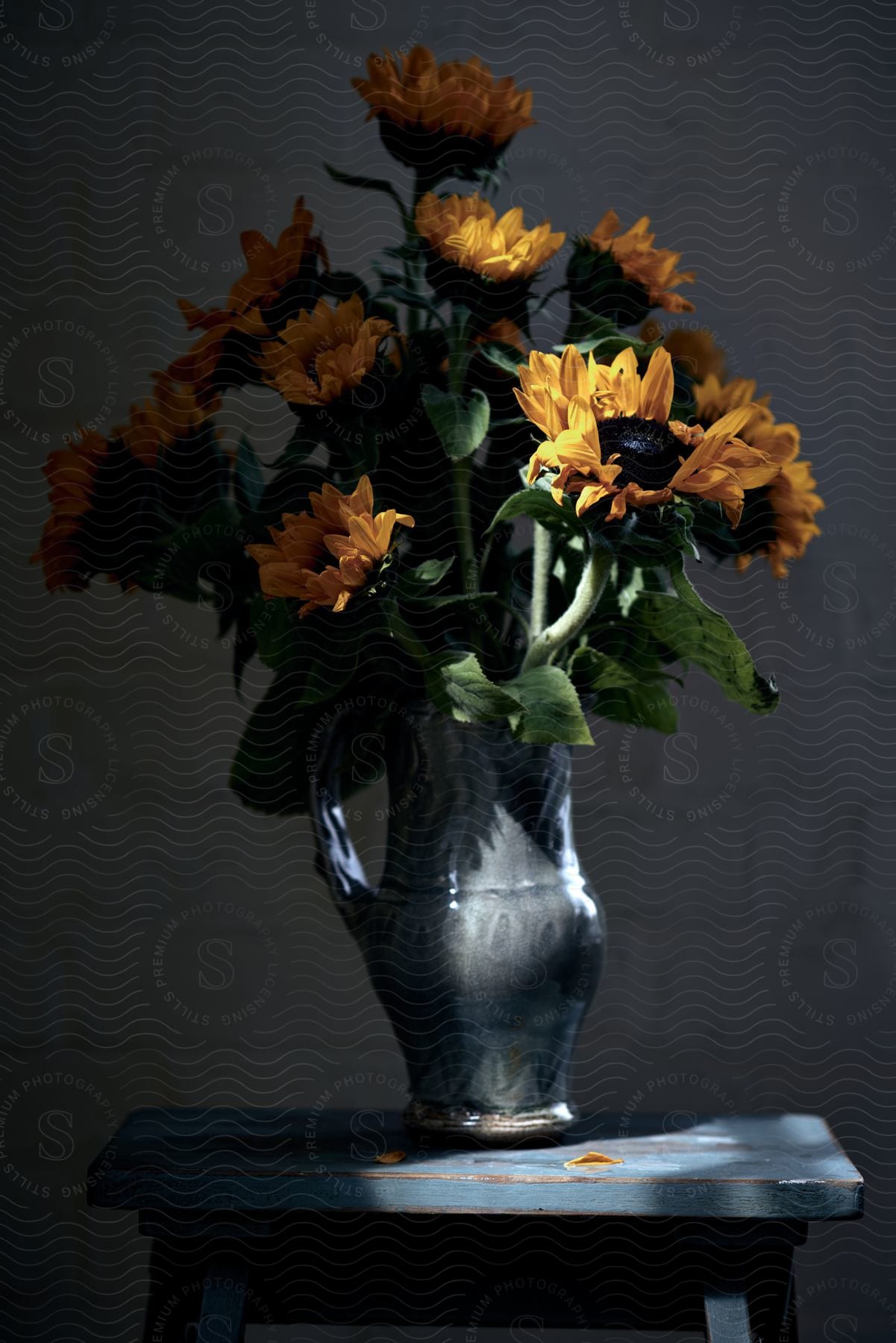 A grey stone pitcher contains a bouquet of sunflowers.