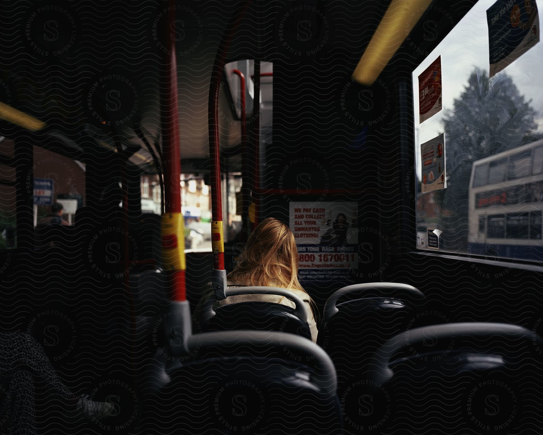 A woman sits on a bus in a city