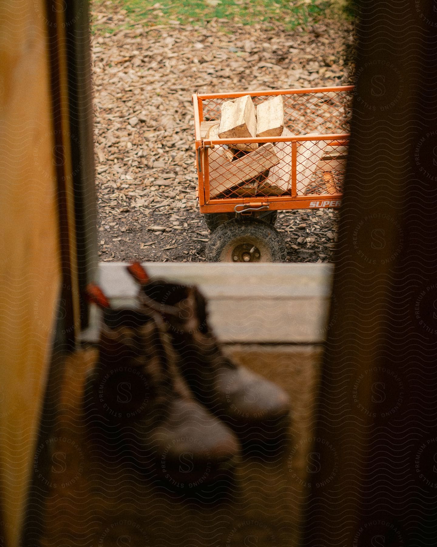 Stock photo of men's leather boots and a cart with firewood next to it.