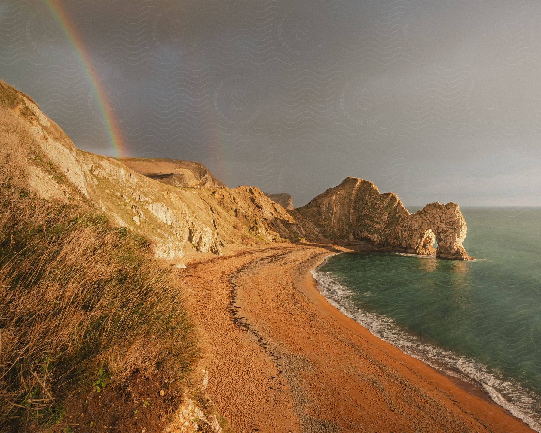 a beach with a rainbow arcing across the sky