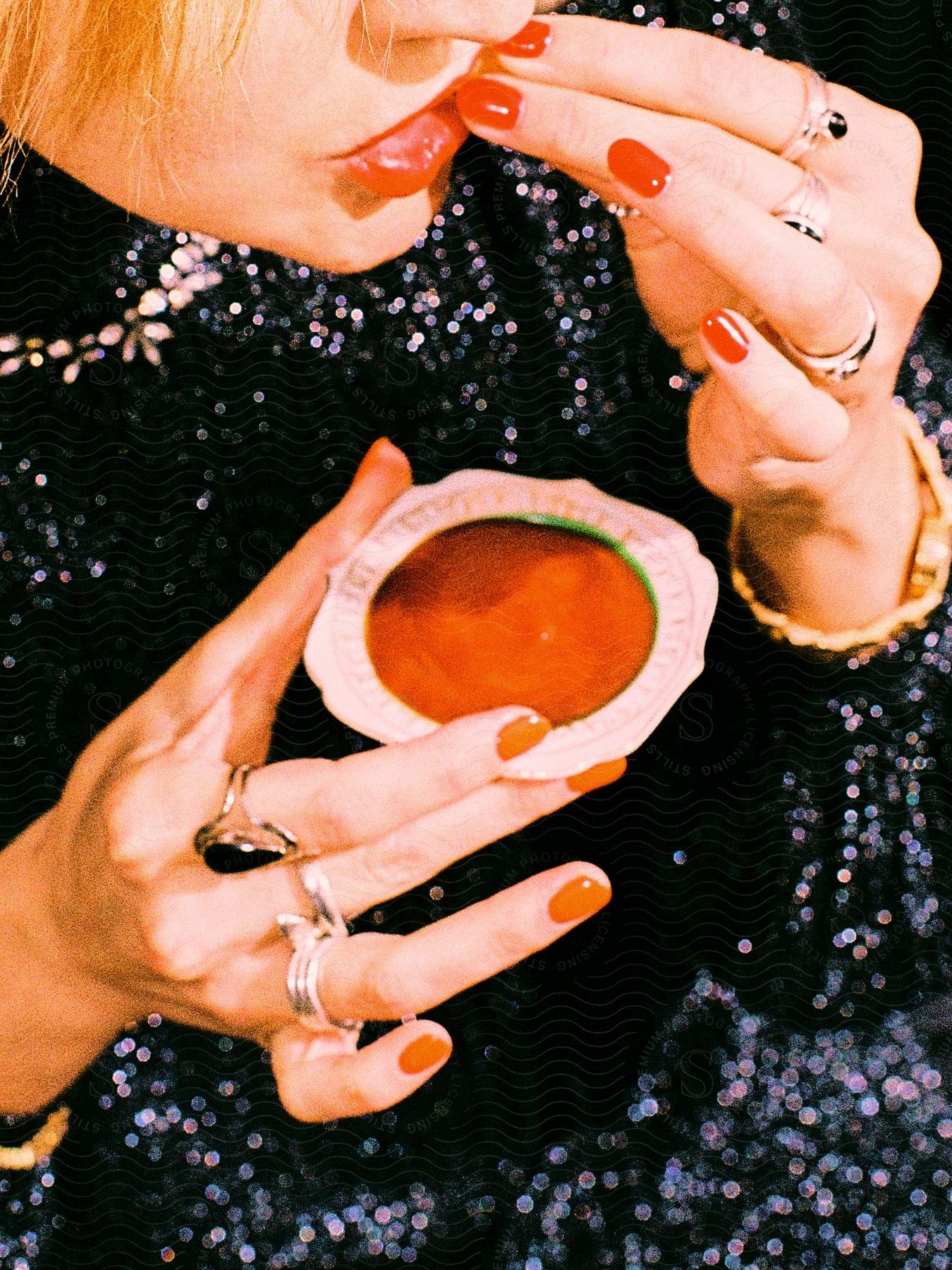 Woman holds a small sauce dish as she eats